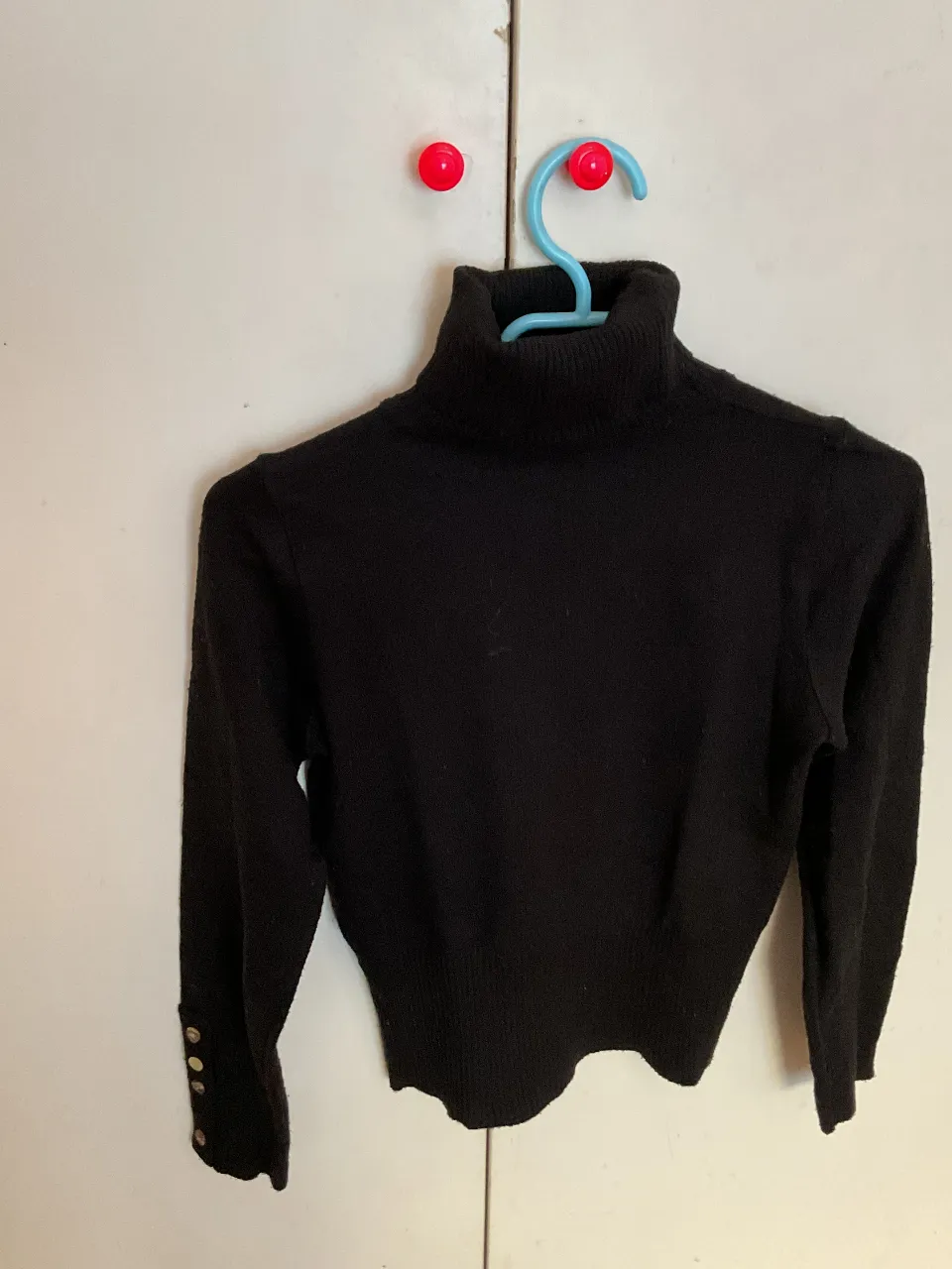 Sweater de cuello alto negro, con detalles de botones dorados en los puños. Ideal para un look elegante y abrigado. con detalles!!
