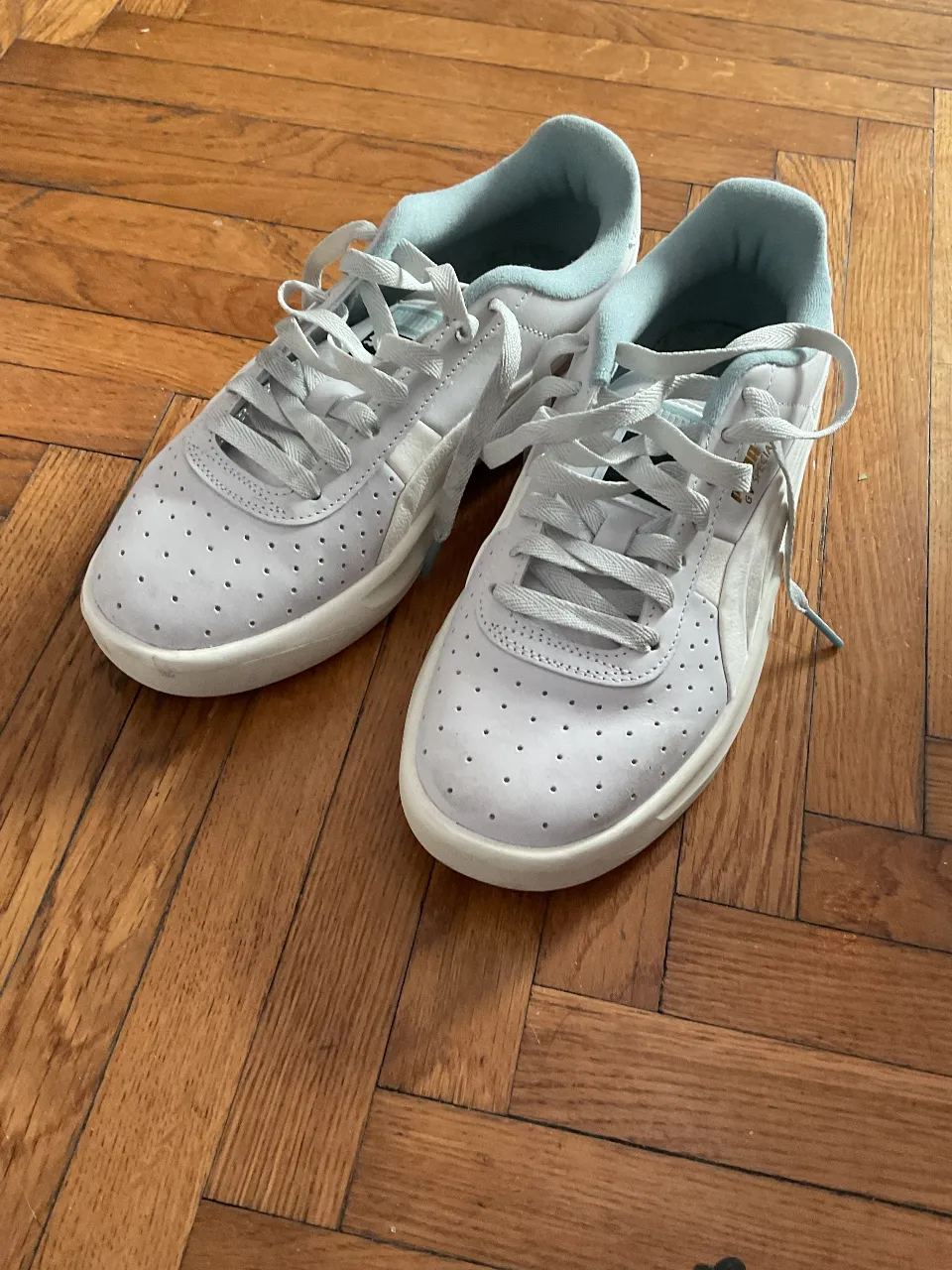 Zapatillas Puma blancas con detalles celestes. Ideales para un look casual y cómodo.