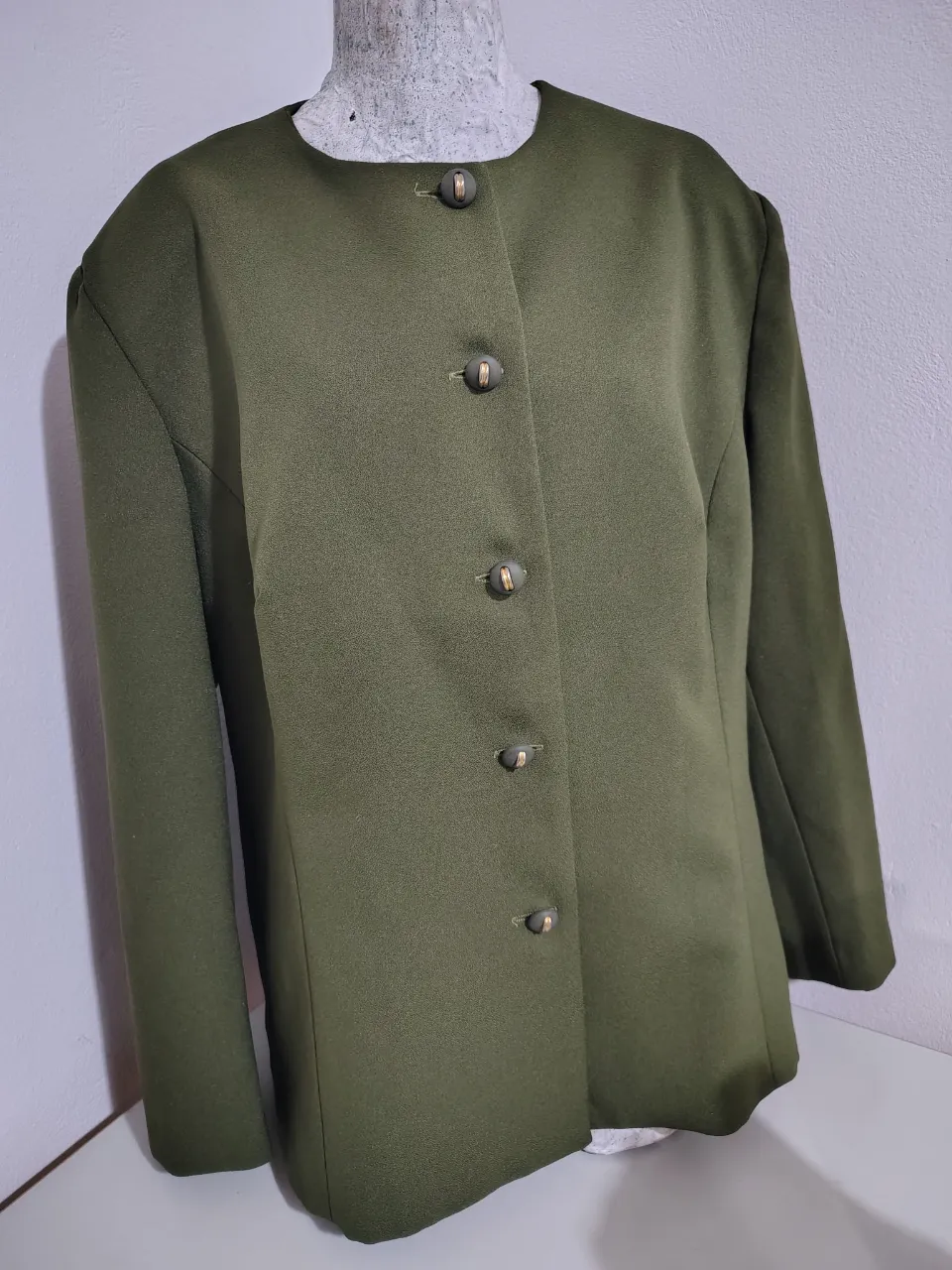 Blazer verde militar, con cuello redondo y botones dorados. Ideal para un look elegante y canchero.