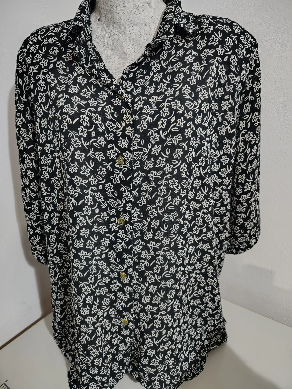 Camisa estampada con flores blancas sobre fondo negro. Manga corta y corte clásico, ideal para un look casual y fresco.
