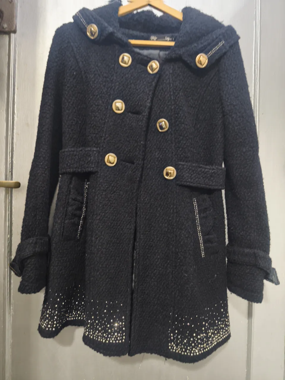 Tapado negro con capucha y detalles dorados. Ideal para el invierno, con un diseño elegante y abrigado. Perfecto para salidas y ocasiones especiales.