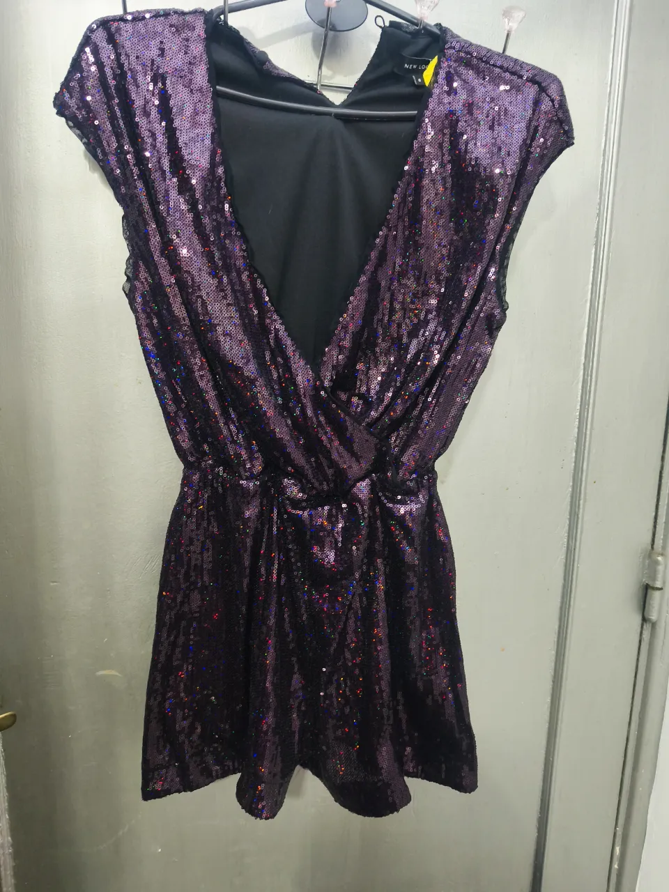 Mono mini de fiesta con lentejuelas violetas. Escote en V pronunciado y detalle drapeado en la cintura. Ideal para eventos especiales. Reino Unido Talle 6 equivale a un XS/ S