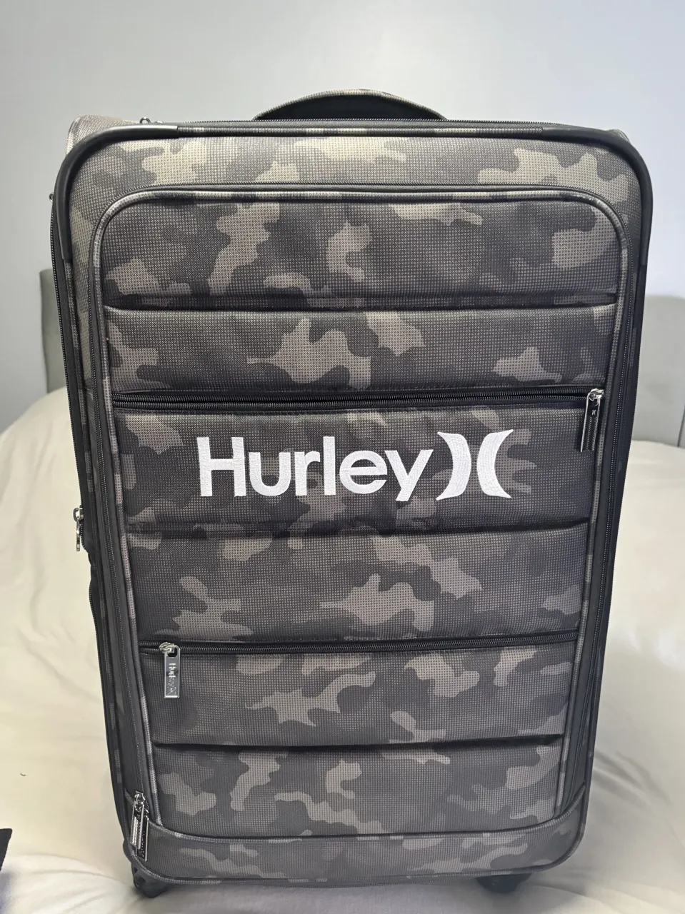 Equipaje de viaje con diseño camuflado en tonos grises y negros. Posee logo de la marca en blanco y múltiples bolsillos con cierres. Ideal para tus próximas aventuras.