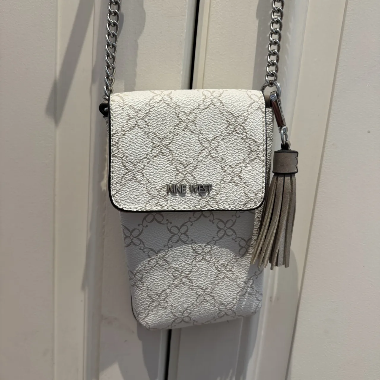 Cartera "bandolera" de Nine West, súper práctica para llevar el celular y tarjetas. Tiene un diseño súper canchero con monograma y un detalle de flecos que le da un toque moderno. Ideal para el día a día o para salir sin cargar mucho.