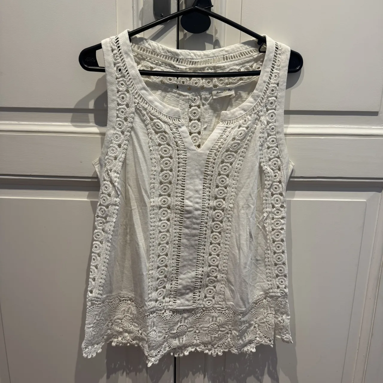 Musculosa blanca de algodón con detalles de crochet y bordados. Escote en V y espalda con diseño calado. Perfecta para un look boho chic o casual de verano.