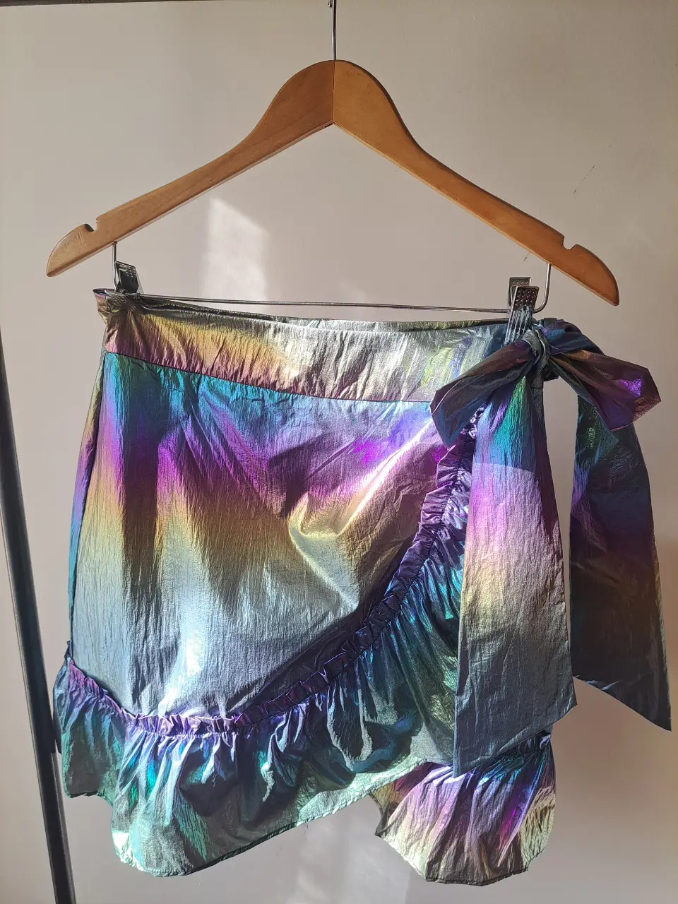 Pollera corta con efecto tornasolado, ideal para un look de fiesta o evento especial. Confeccionada con un tejido brillante y detalles de volados, esta pollera es una pieza única y llamativa.
