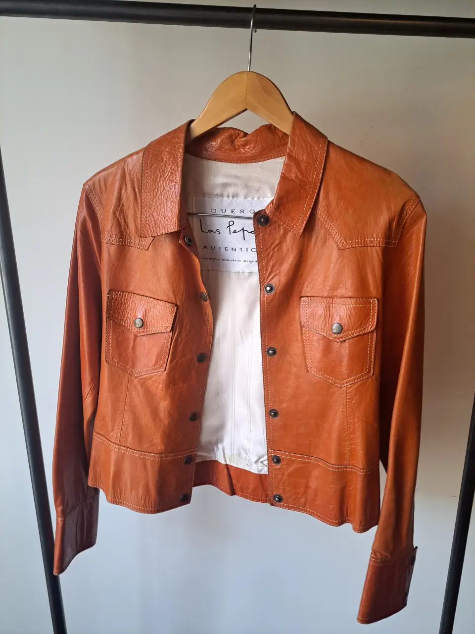 Campera de cuero naranja de la marca Las Pepas, con detalles de costura y botones metálicos. Ideal para un look retro y canchero.