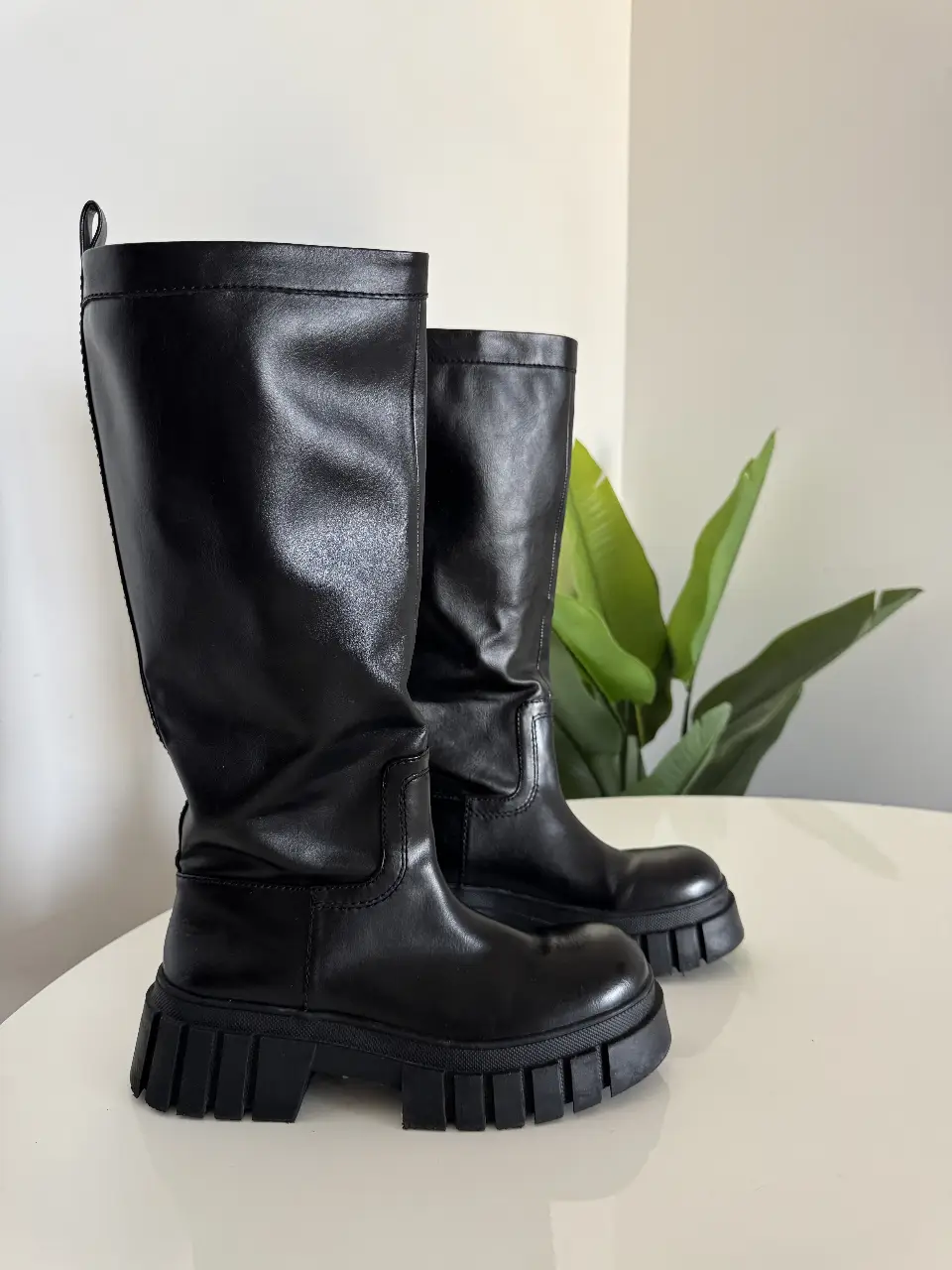 Botas negras de caña alta con suela gruesa. Ideales para un look moderno y urbano.