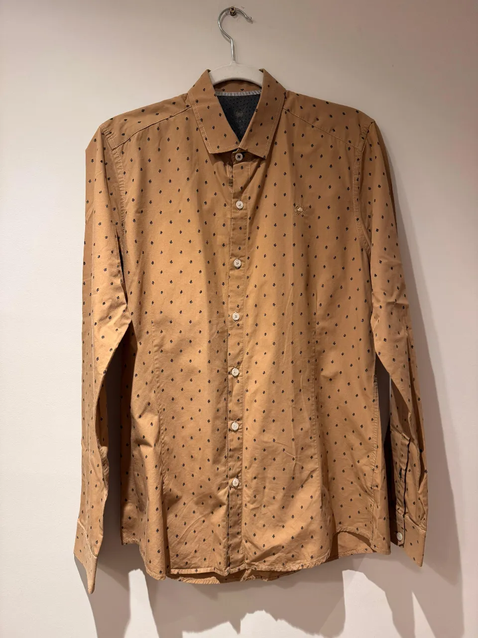 Camisa de hombre con estampado de pequeños detalles en color negro sobre un fondo marrón. Corte clásico, ideal para un look casual o semi-formal.