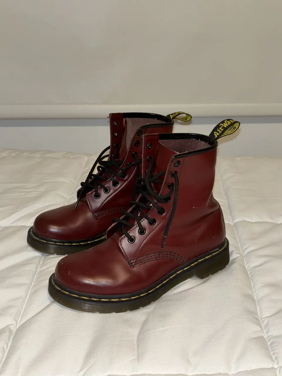 Borcegos Dr. Martens color bordó, con cordones negros y detalles amarillos en la parte trasera. Ideales para un look rocker o casual.