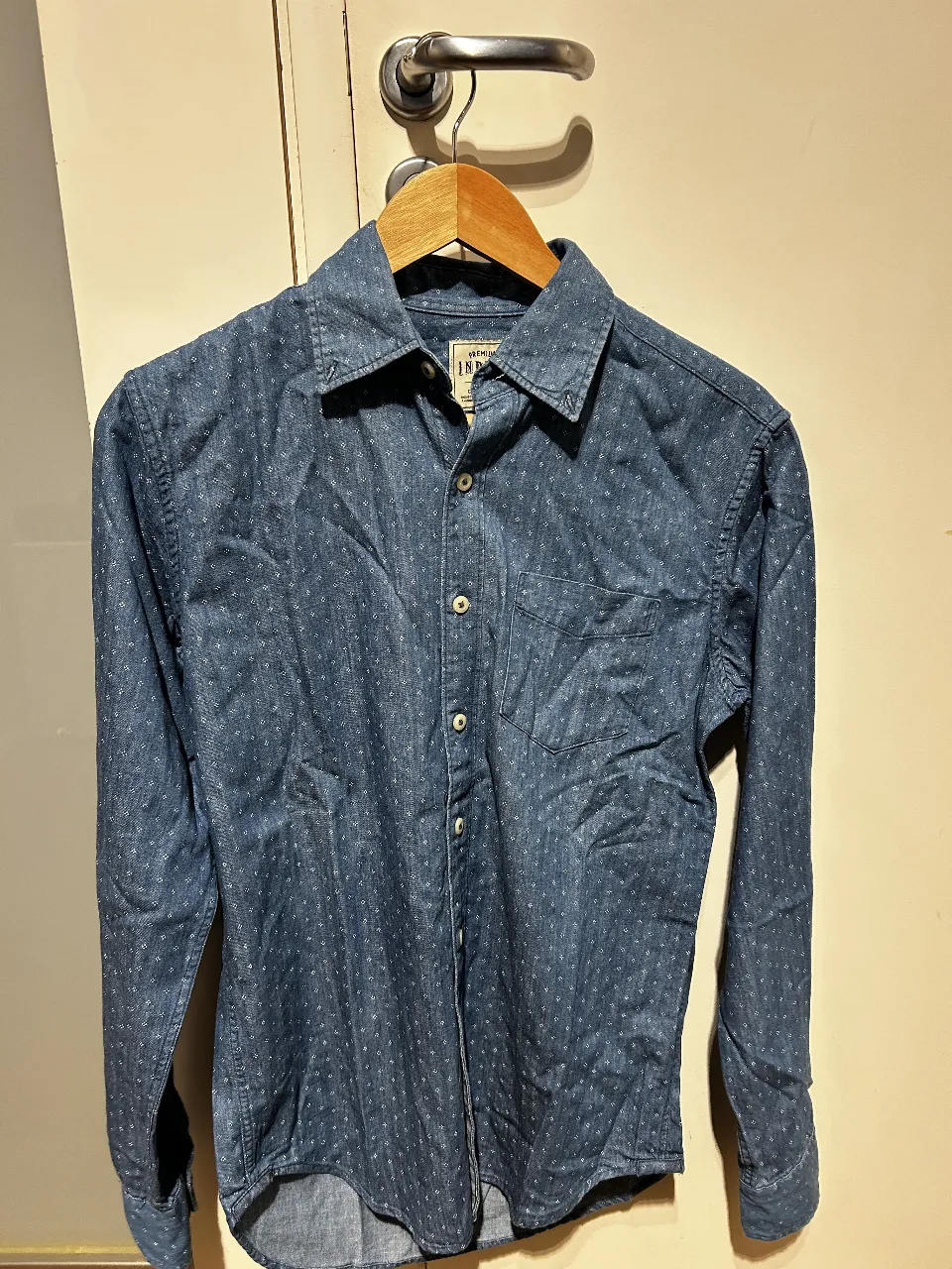 Camisa de hombre de jean azul con estampado de puntos blancos. Corte clásico, manga larga y bolsillo en el pecho. 