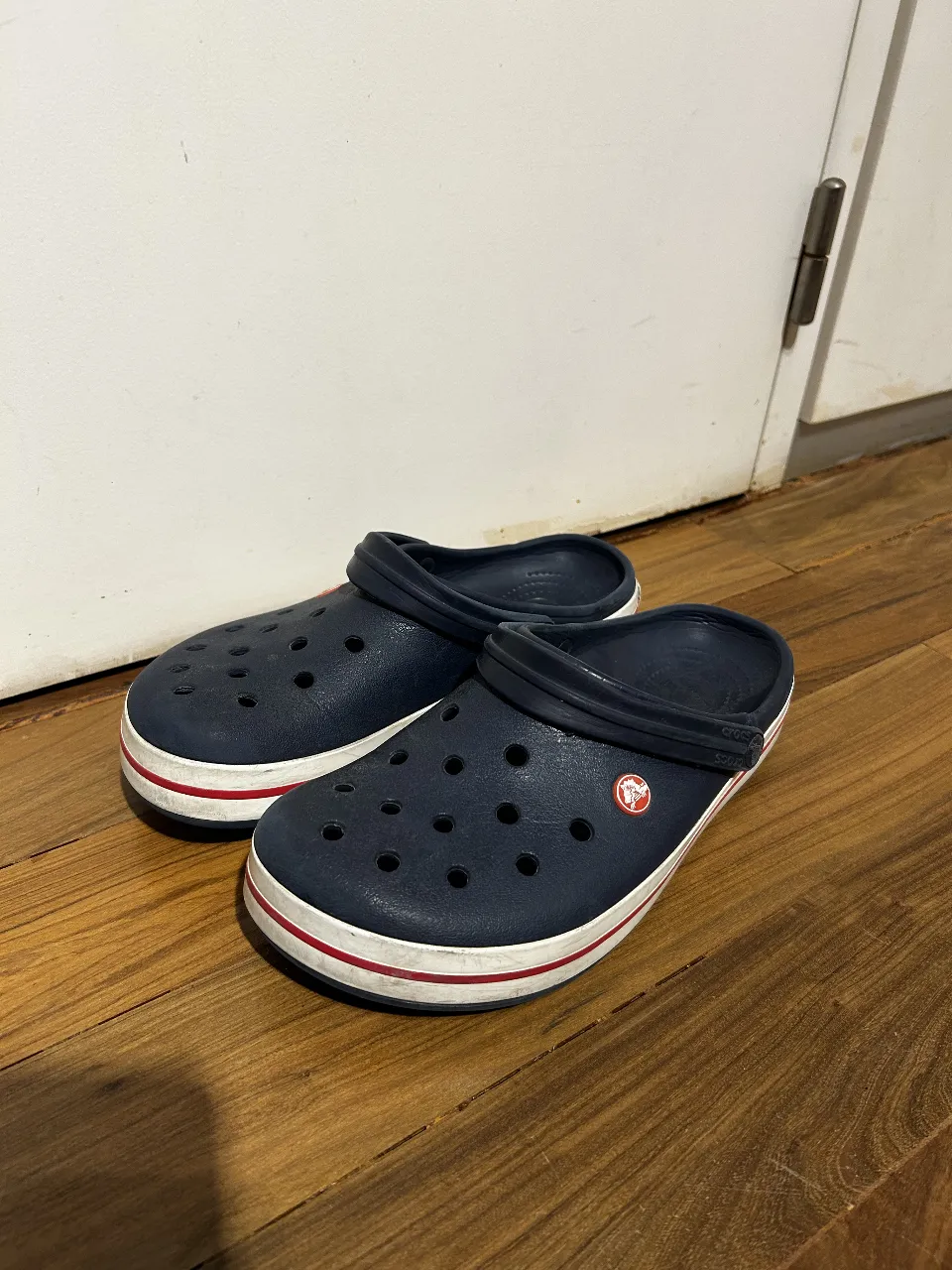 Zuecos Crocs azules con detalles blancos y rojos. Ideales para un look casual y cómodo.
