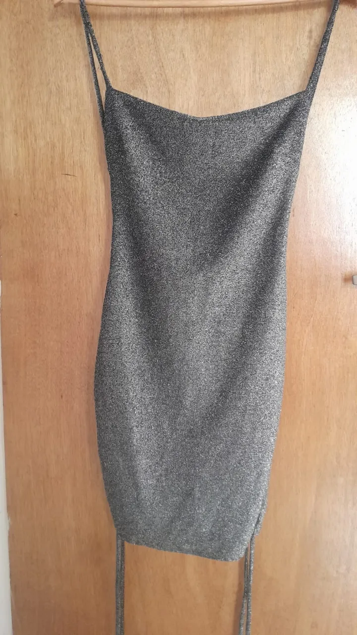 Vestido plateado con brillos, tiras finas y espalda descubierta.