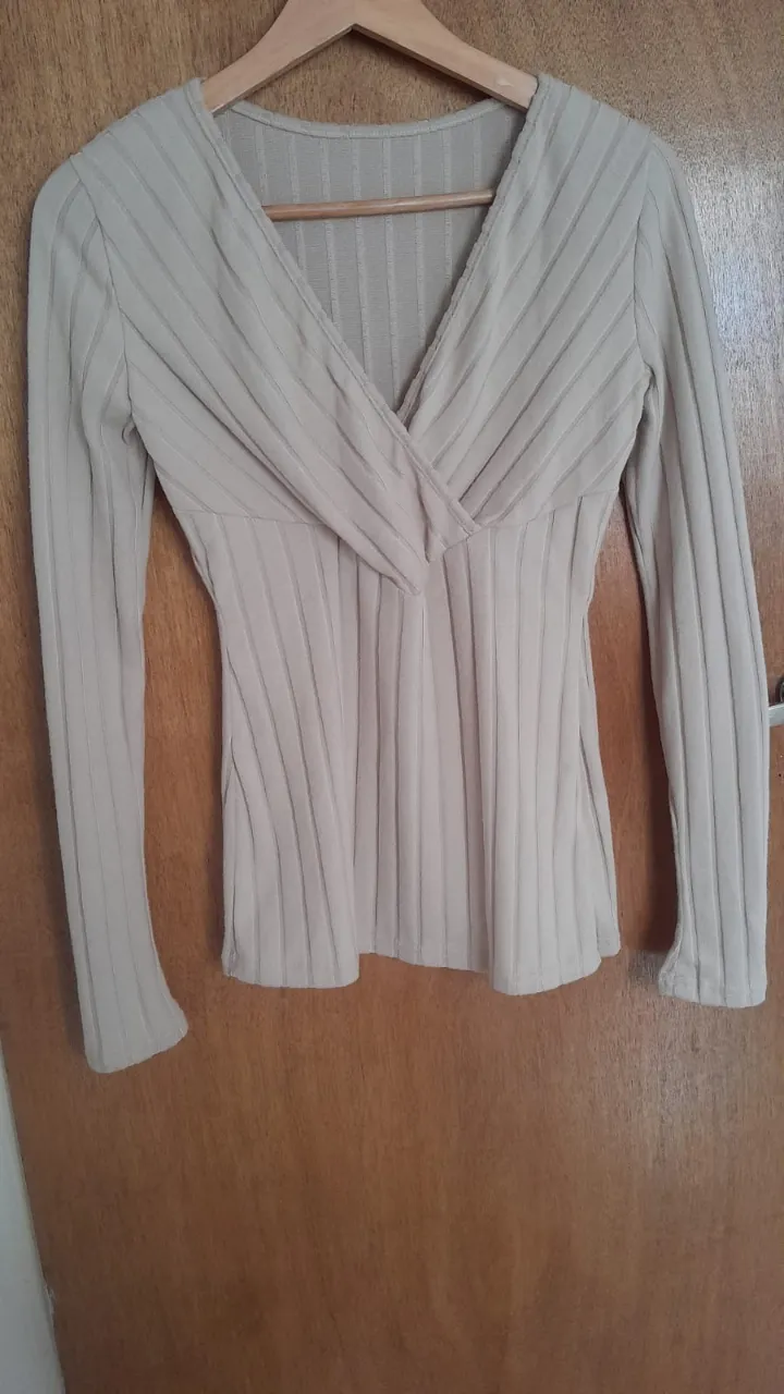 Remera de manga larga color beige con escote cruzado y textura acanalada.