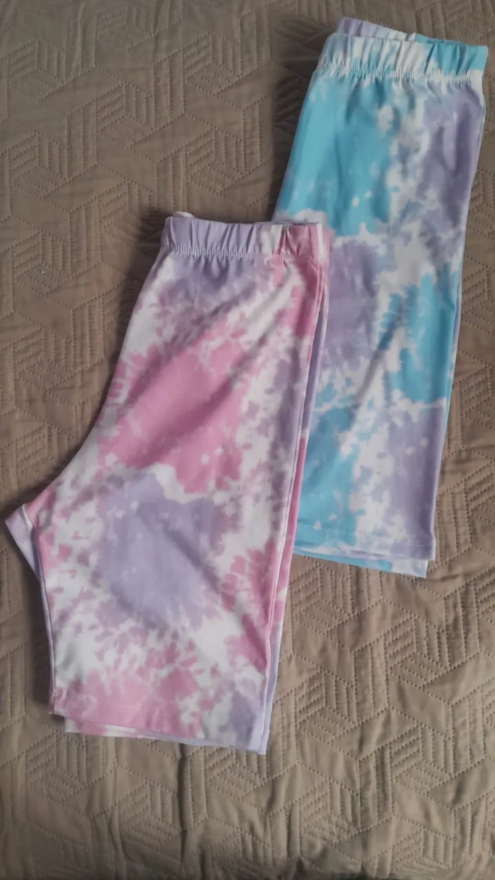 Conjunto de dos shorts de ciclista con estampado tie-dye en tonos pastel. Uno es rosa y lila, el otro es celeste y lila. Ambos tienen cintura elastizada.