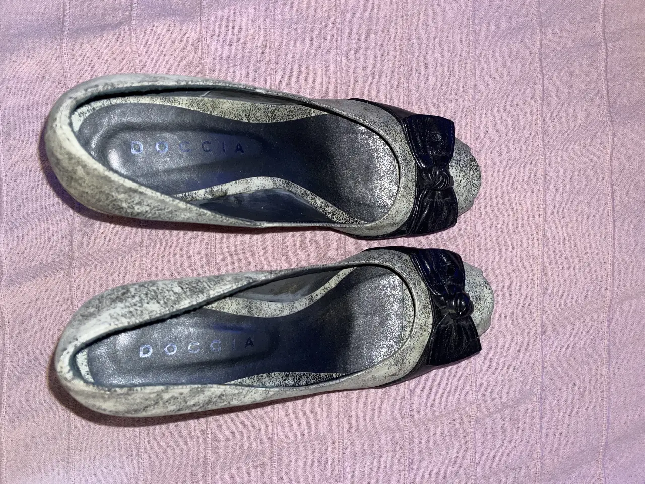 Elegantes zapatos de tacón DOCCIA, con diseño bicolor en blanco y negro. Detalles de moño en la punta y suela con desgaste. Ideales para eventos formales o para darle un toque sofisticado a tu look.