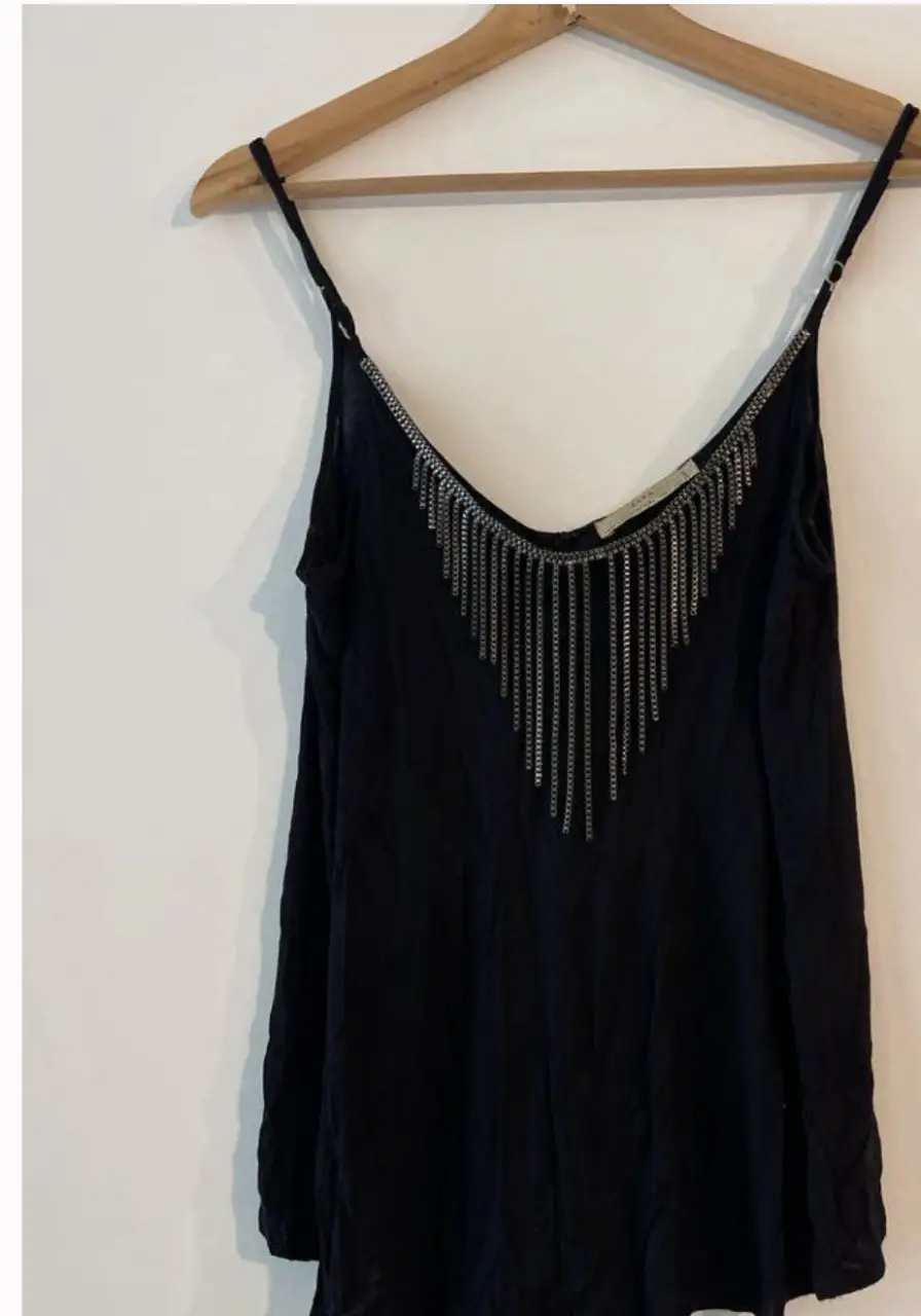 Top negro con detalle de cadenas plateadas en el escote. Ideal para una salida nocturna o evento especial. Marca Zara.