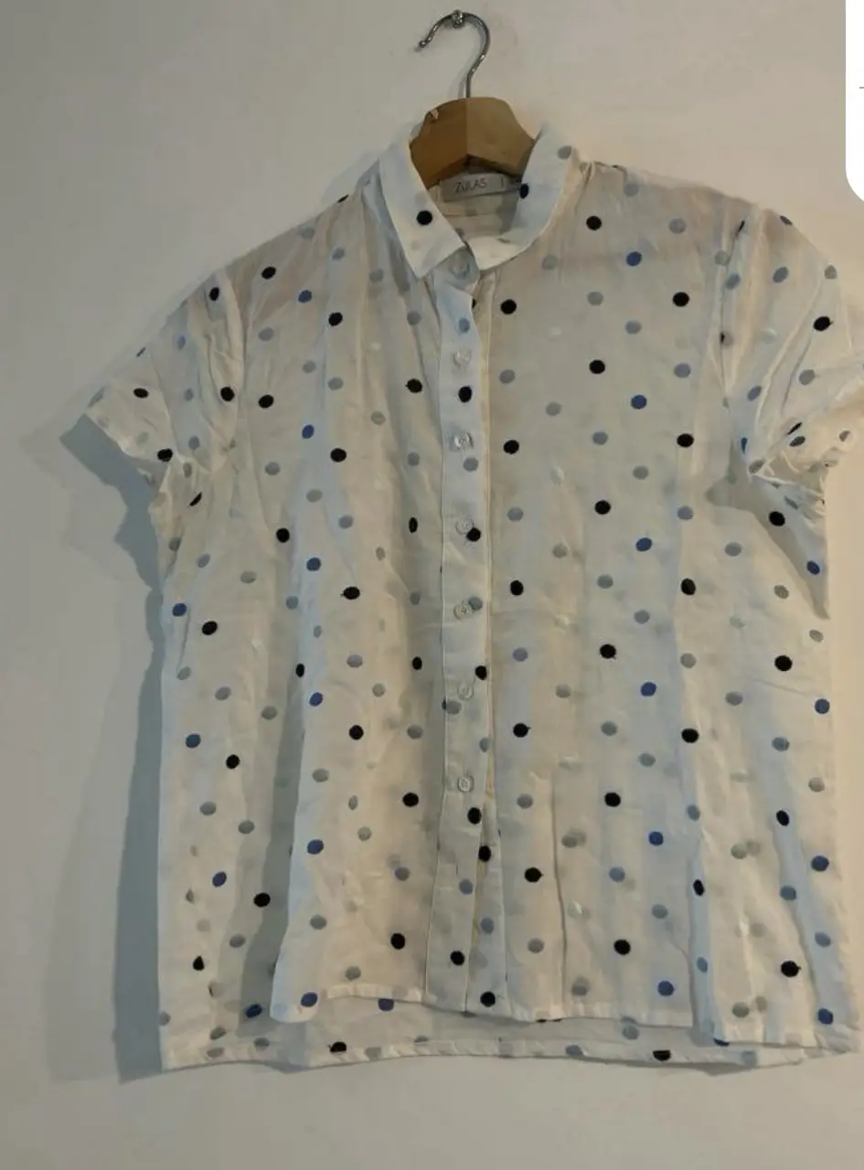 Blusa de mujer Zara, blanca con lunares azules y negros. Manga corta y cuello camisero. Ideal para un look casual y fresco.