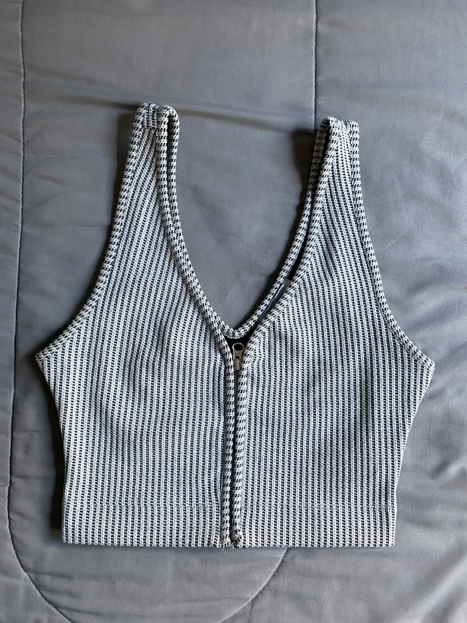 Top de mujer con cierre frontal y diseño a rayas en blanco y negro. Ideal para un look casual y moderno.