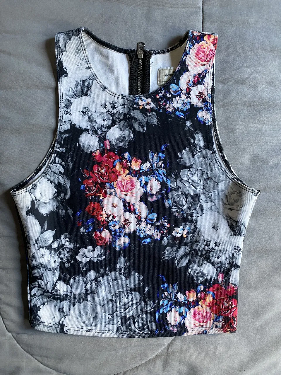 Top de mujer con estampado floral en tonos oscuros y vivos. Diseño sin mangas con cierre en la parte trasera  Ideal para un look moderno y femenino.
