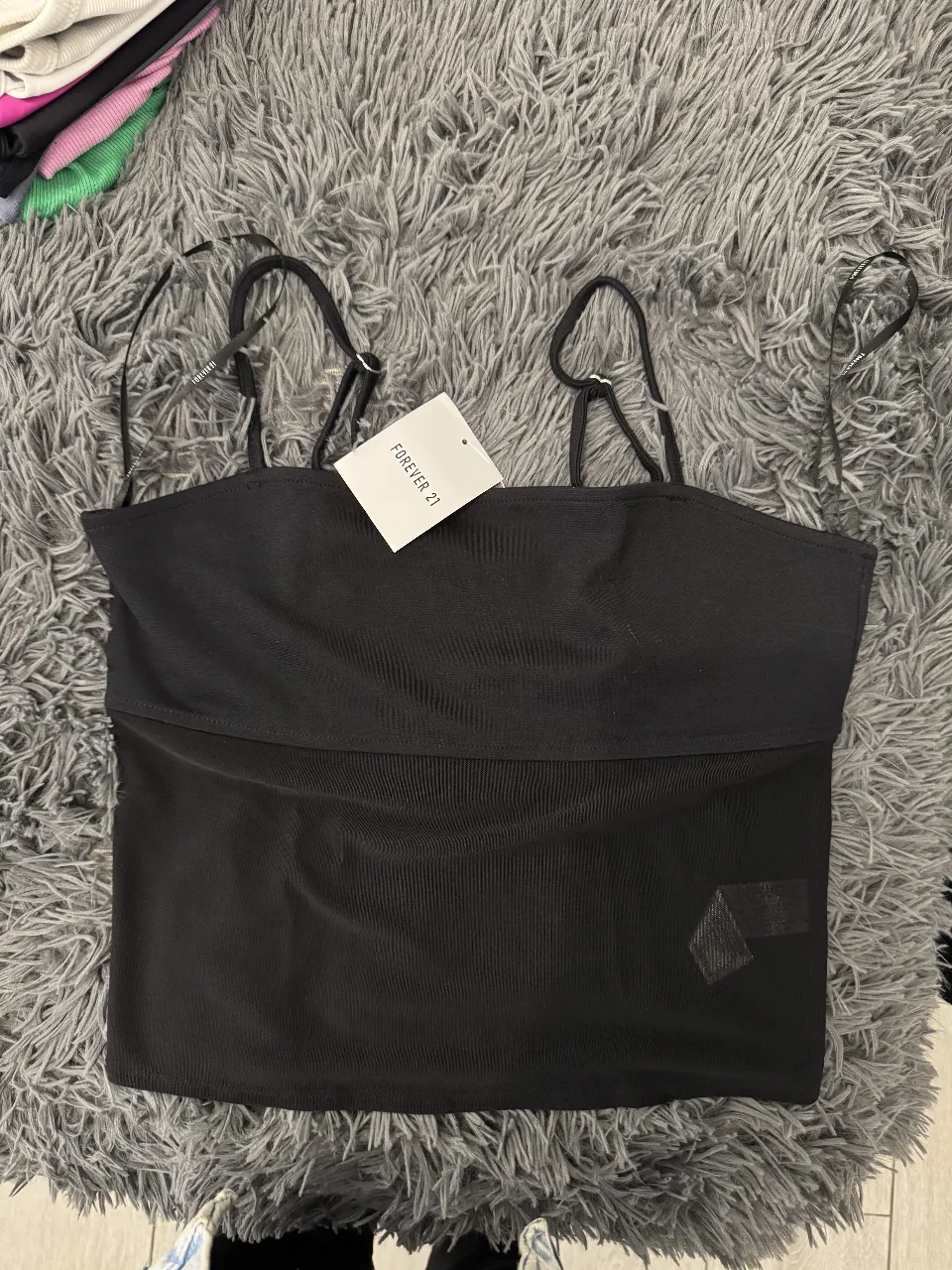 Top negro de Forever 21, con tirantes finos y detalle de tela en la parte superior. Ideal para un look casual y moderno.