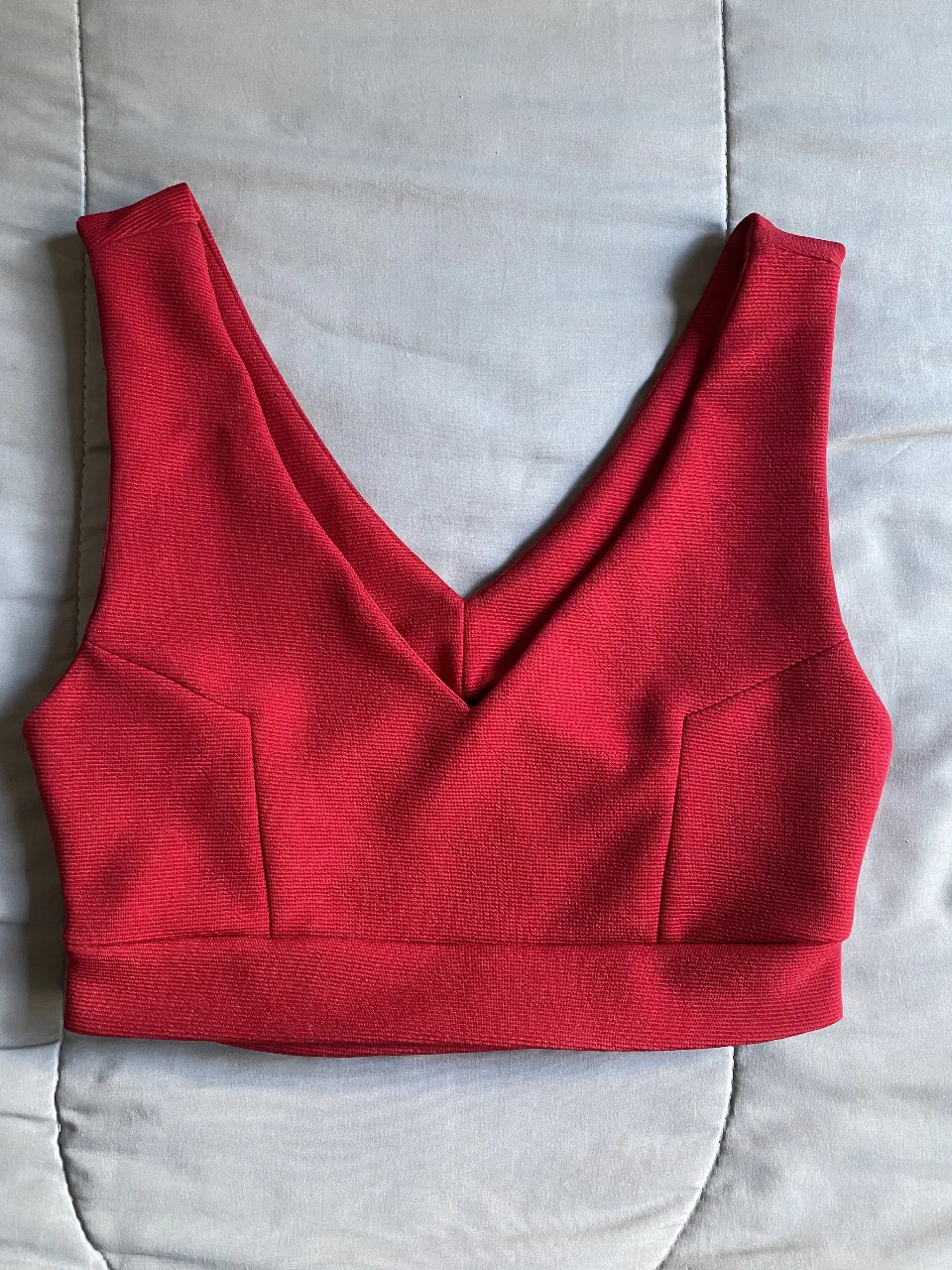 Top deportivo rojo con escote en V, ideal para actividades de bajo impacto. Diseño ajustado y moderno.