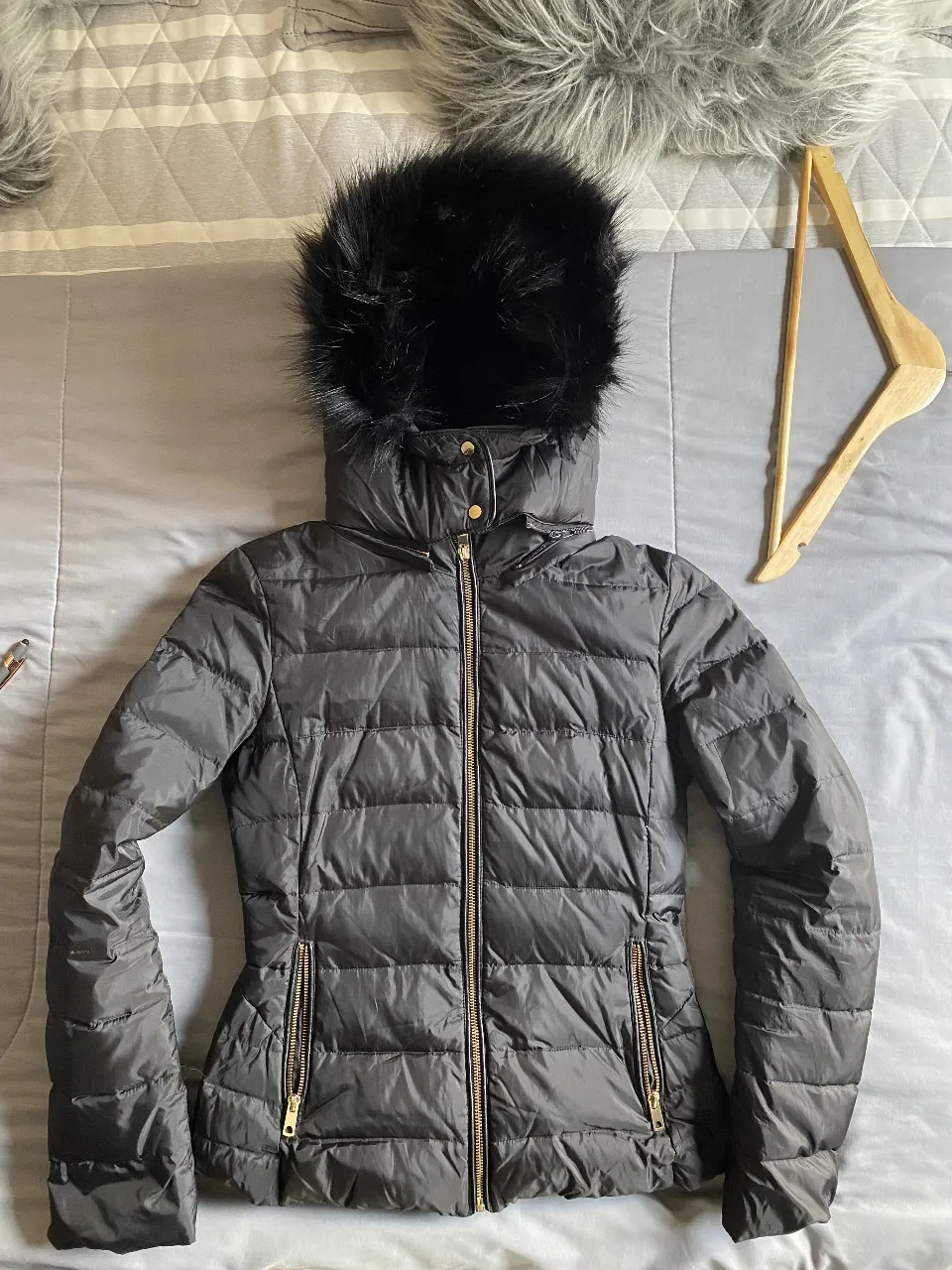 Campera negra acolchada con capucha de piel sintética. Posee cierre y bolsillos con cierre dorado. Ideal para el invierno. 