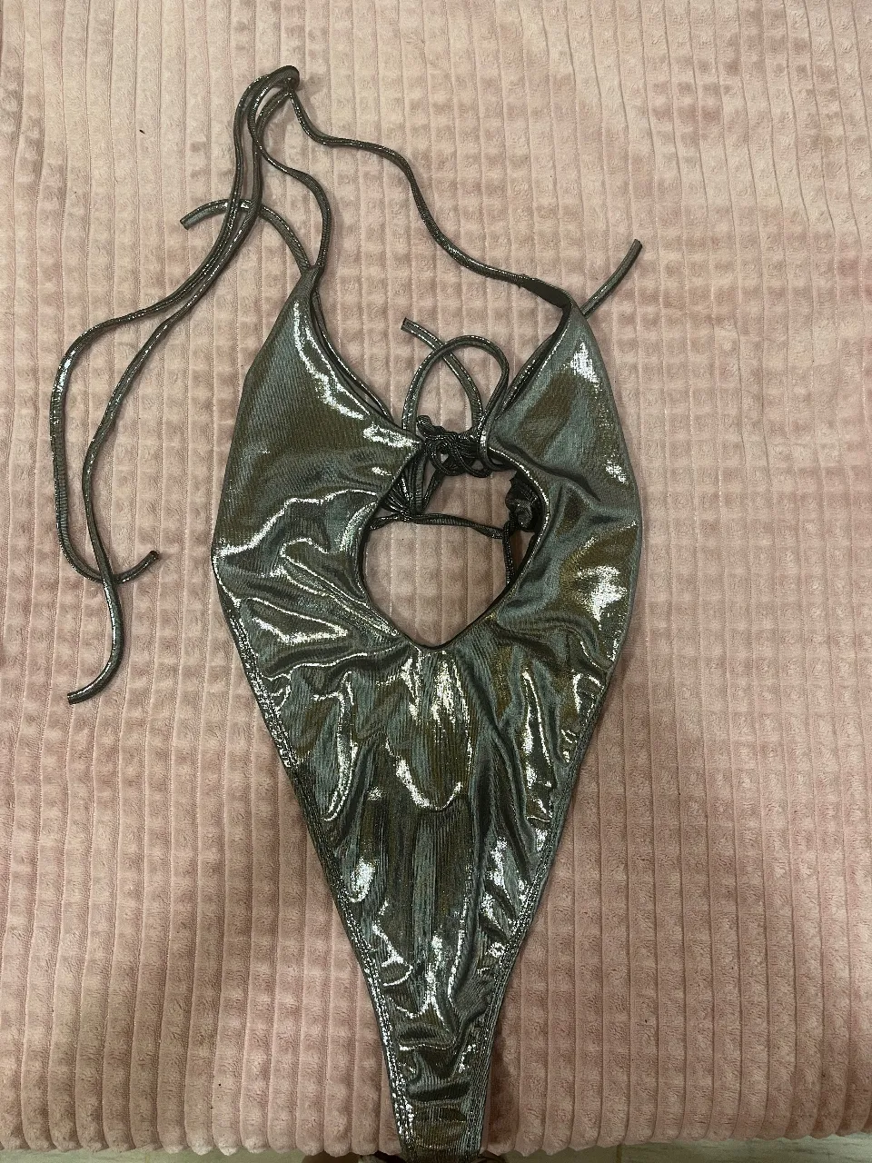 ¡Luce espectacular con este traje de baño plateado metálico! Su diseño audaz con corte profundo y tiras ajustables te hará destacar en la playa o la piscina. Perfecto para sentirte segura y a la moda.