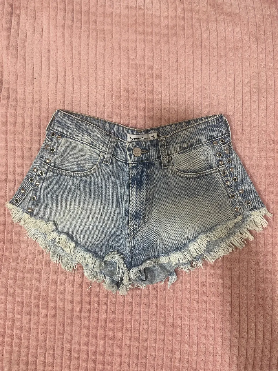 Shorts de jean tiro alto con tachas y flecos. Un básico canchero para el verano, ideal para combinar con tops o remeras.