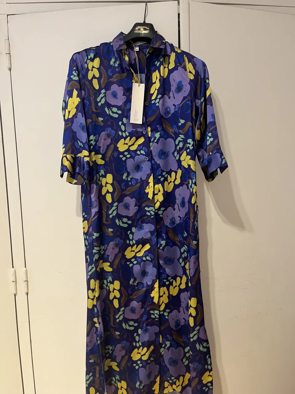 Vestido largo azul con estampado floral en tonos violeta y amarillo. Posee cuello camisero y botones al frente. TALLE 40 