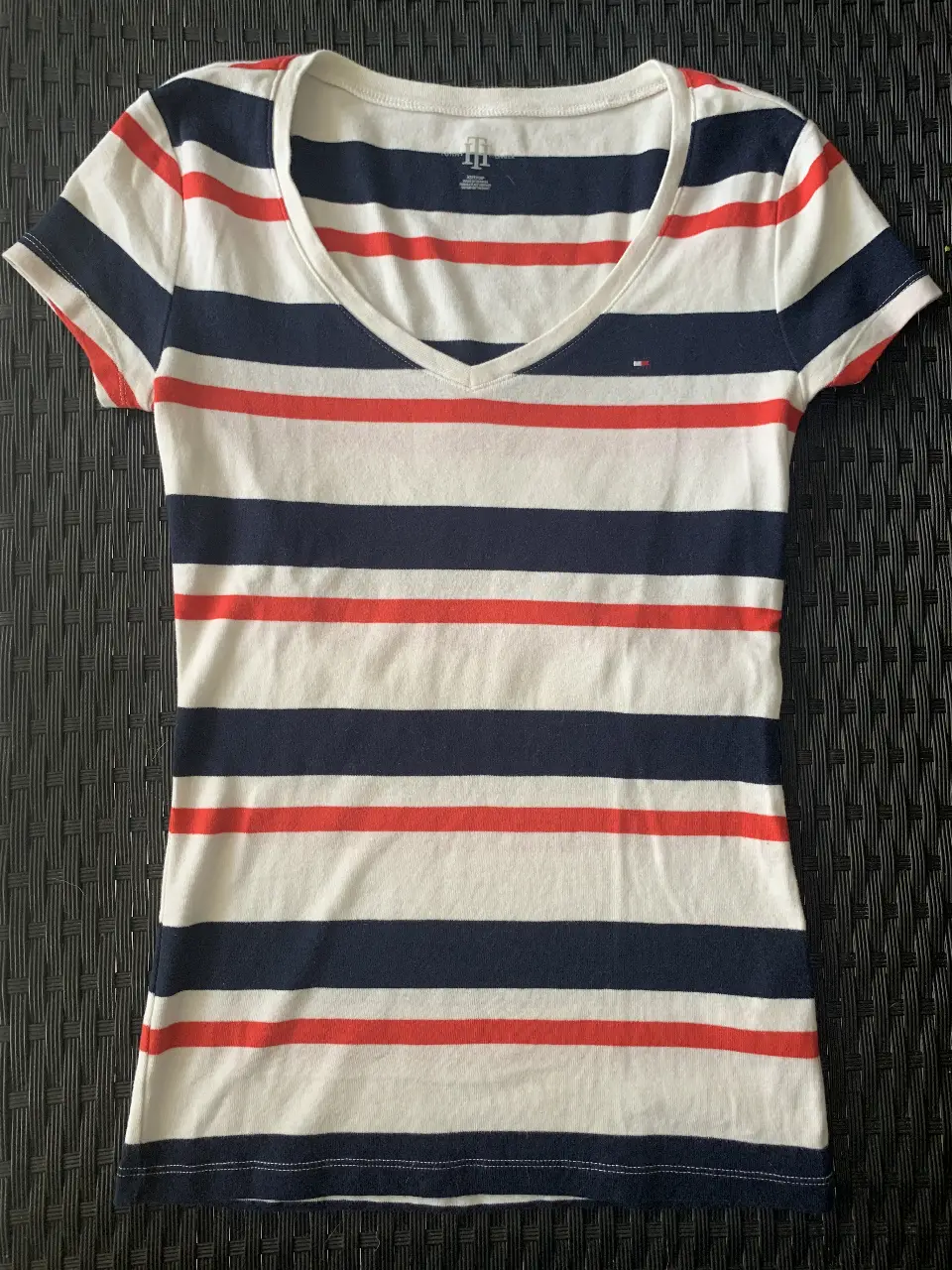 Remera Tommy Hilfiger a rayas horizontales en blanco, azul y rojo. Corte clásico con cuello en V. Ideal para un look casual y fresco.