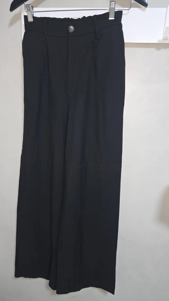 Pantalón negro de vestir, tiro alto con elástico en la cintura. Corte ancho y moderno, ideal para un look elegante y cómodo.