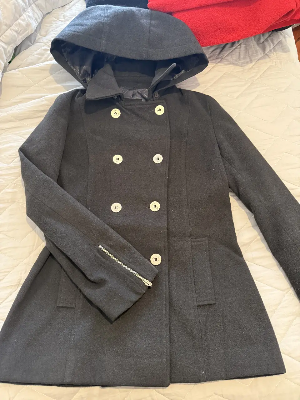 Tapado gris oscuro con capucha, doble botonadura y cierre en las mangas. Ideal para el invierno.