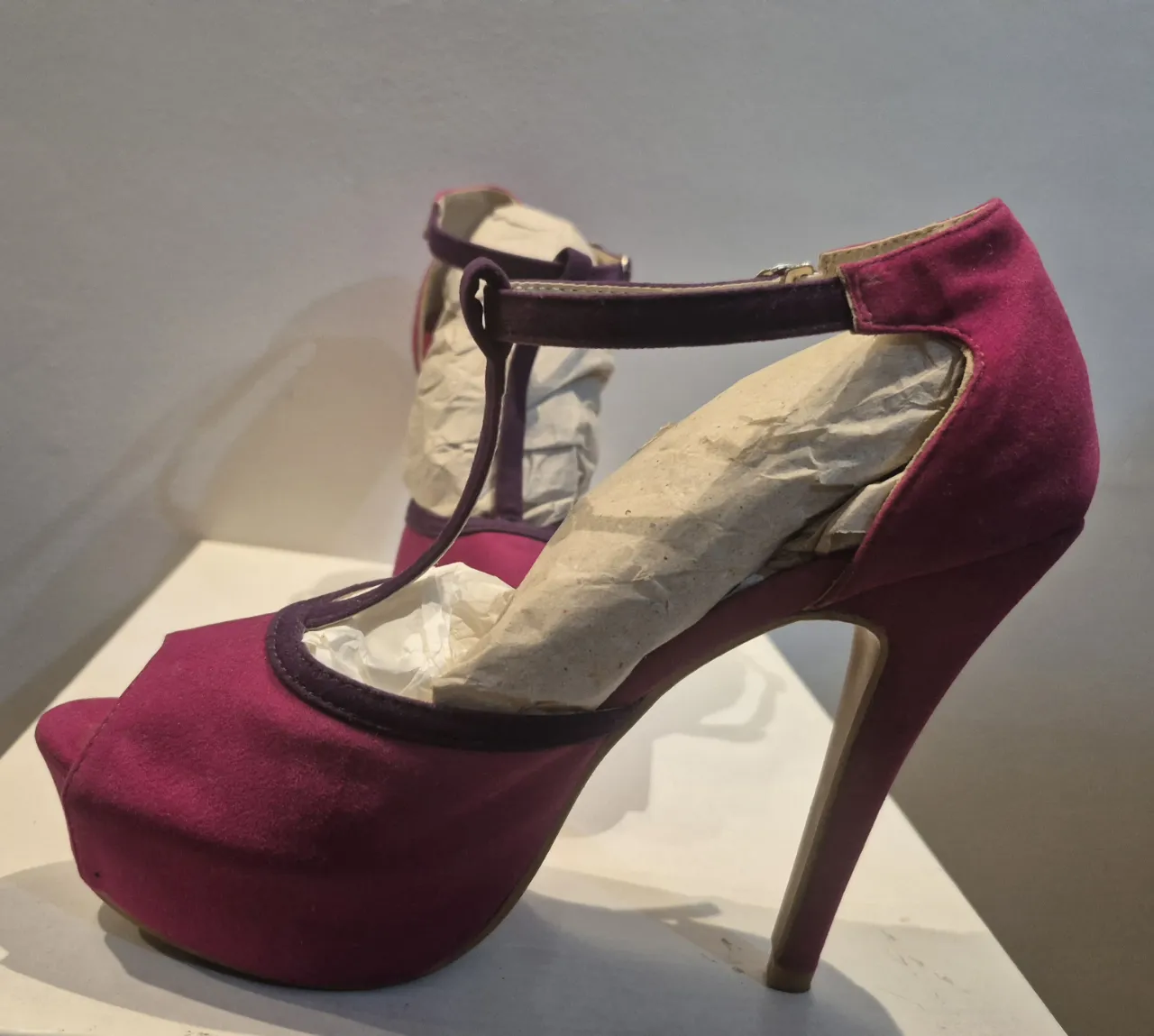 Zapatos con taco y plataforma color fucsia con detalles en violeta. Tienen una tira que cruza el empeine y se abrocha al tobillo. Ideales para darle un toque glamoroso a cualquier look. Veranos. 