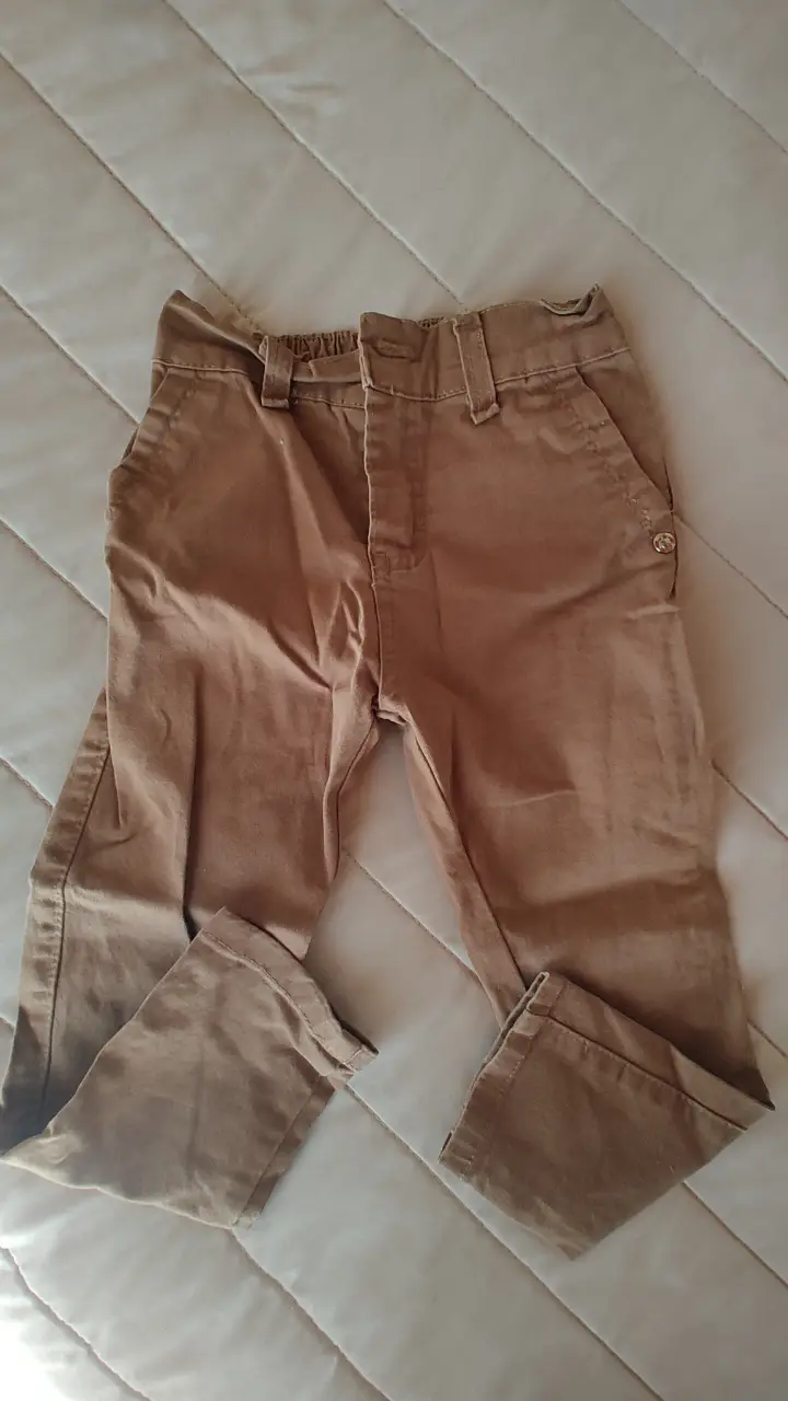 Pantalón para niño, color marrón. Ideal para un look casual y cómodo. Confeccionado en tela resistente y diseño clásico. Tiene 52cm de largo y 25cm de cintura, también tiene elástico en la parte de atrás de la cintura. 