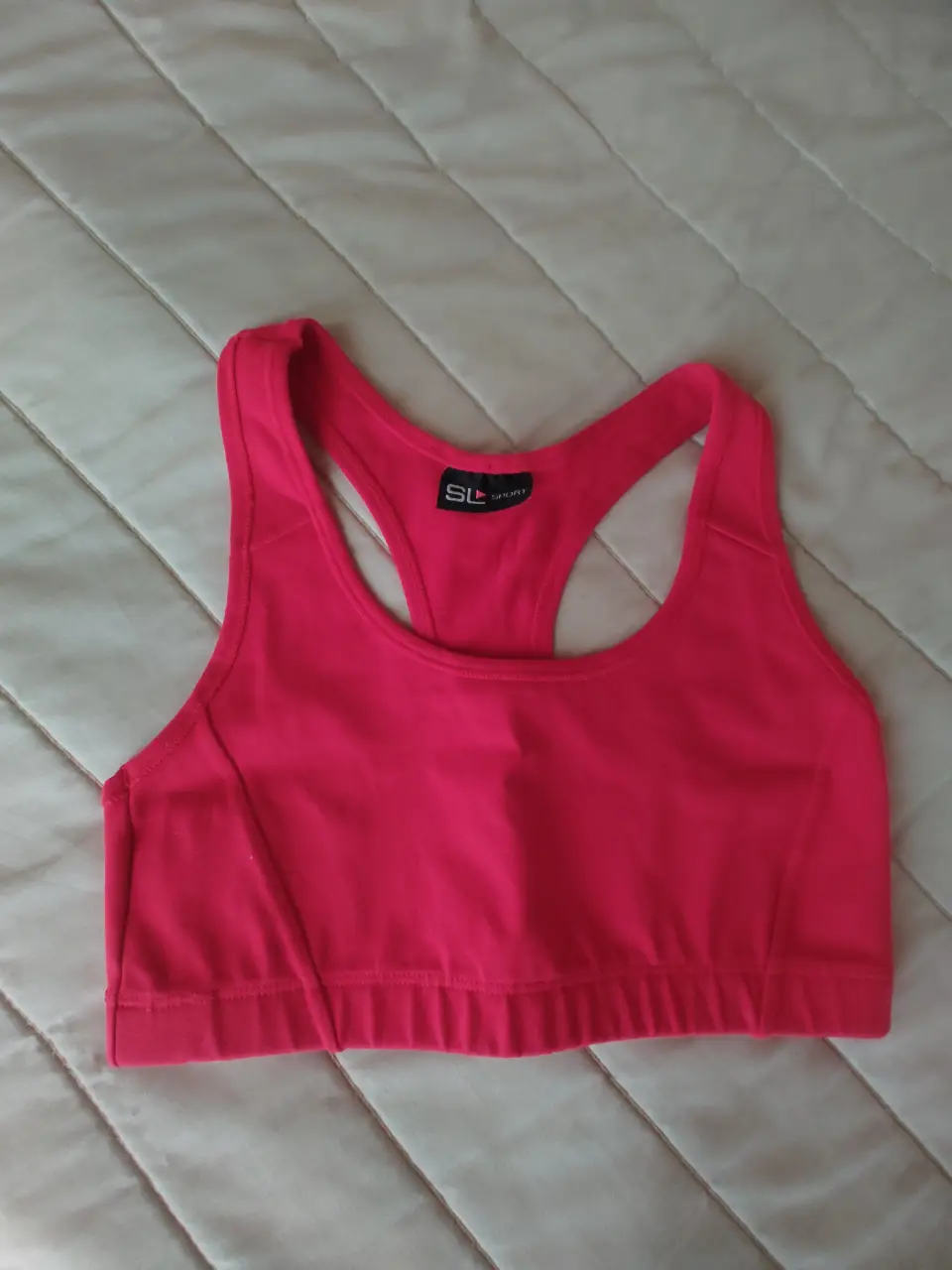 Top deportivo SL Sport rojo para mujer. Confeccionado con tejido suave y elástico para mayor comodidad y libertad de movimiento. Diseño con espalda deportiva y logo de la marca.