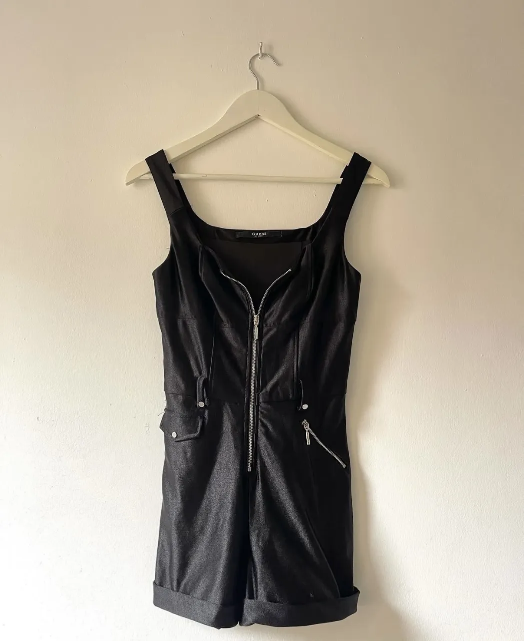 Mono Guess corto. 
Con cierre frontal metálico y detalles de bolsillos.  Terminación doblada en el short. Tela con leve brillo. Está impecable! 