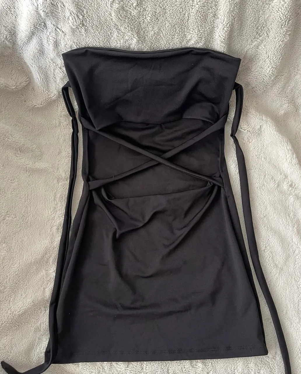 Vestido negro strapless con detalles cruzados en el frente. 