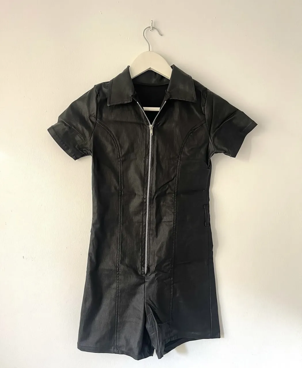 Mono negro de cuero sintético con cierre al frente y cuello camisero. 