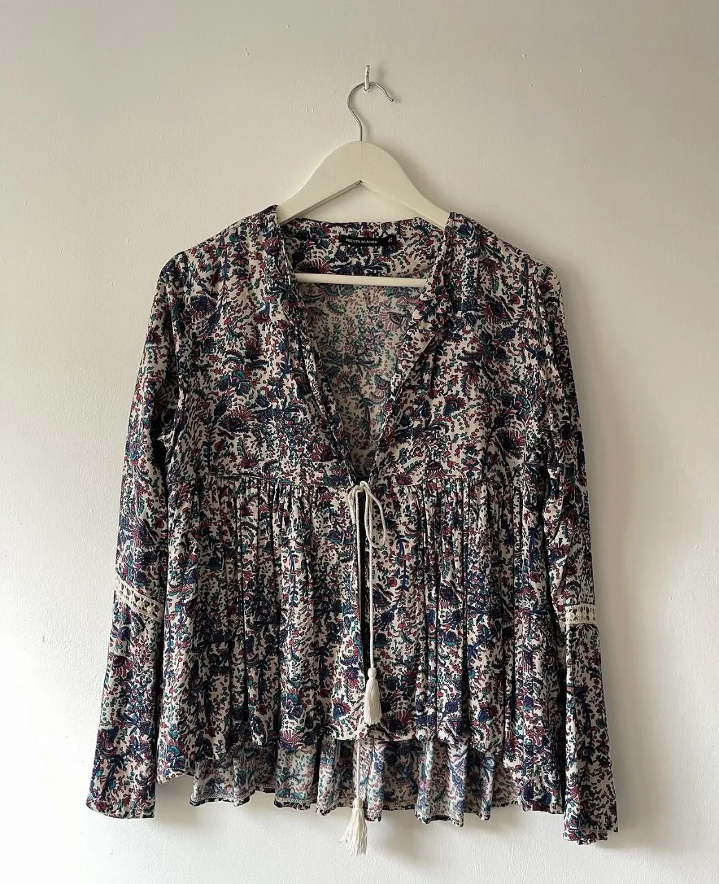 Blusa Cuesta Blanca, estampada con detalles de crochet en las mangas y cordón con flecos en el escote. 