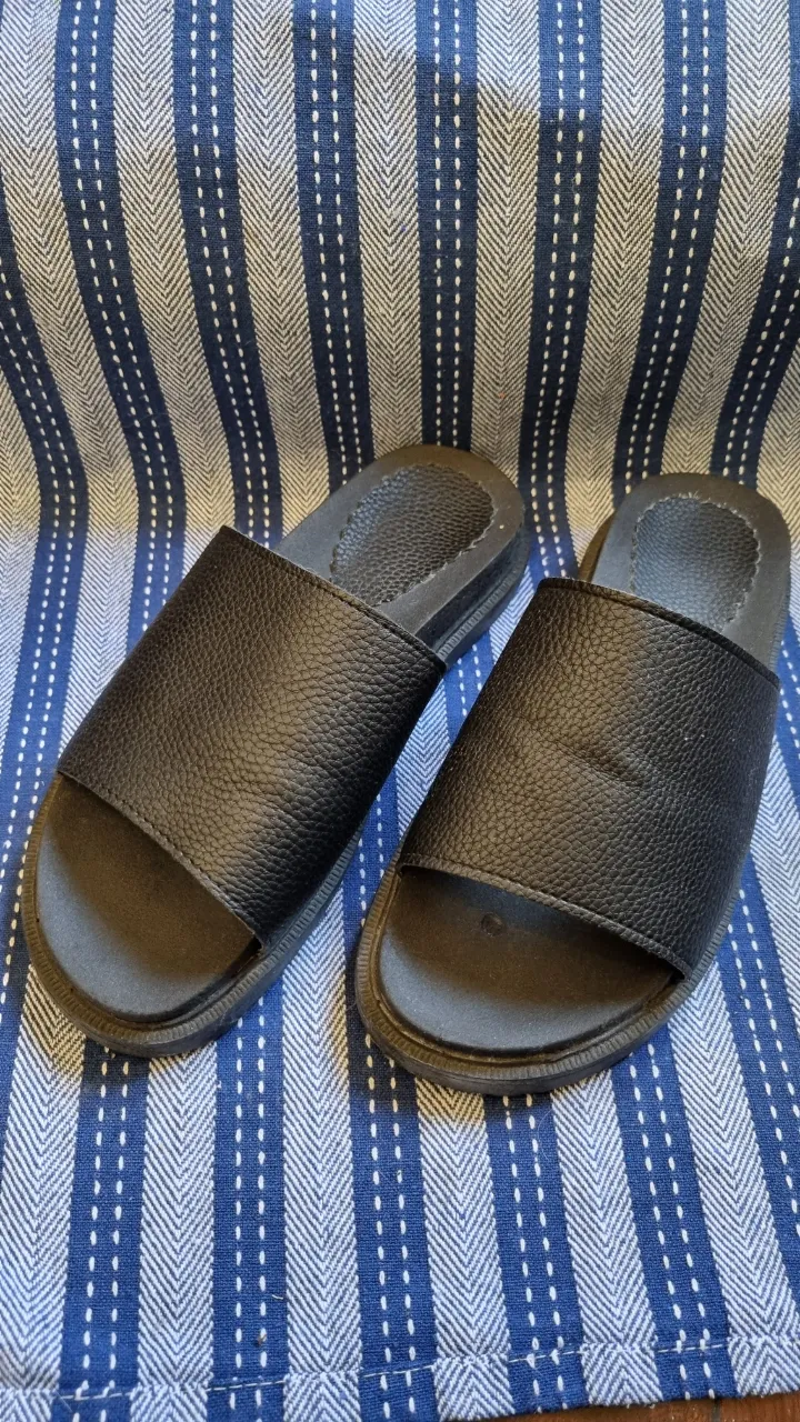 Ojotas negras de cuero sintético con tira ancha.