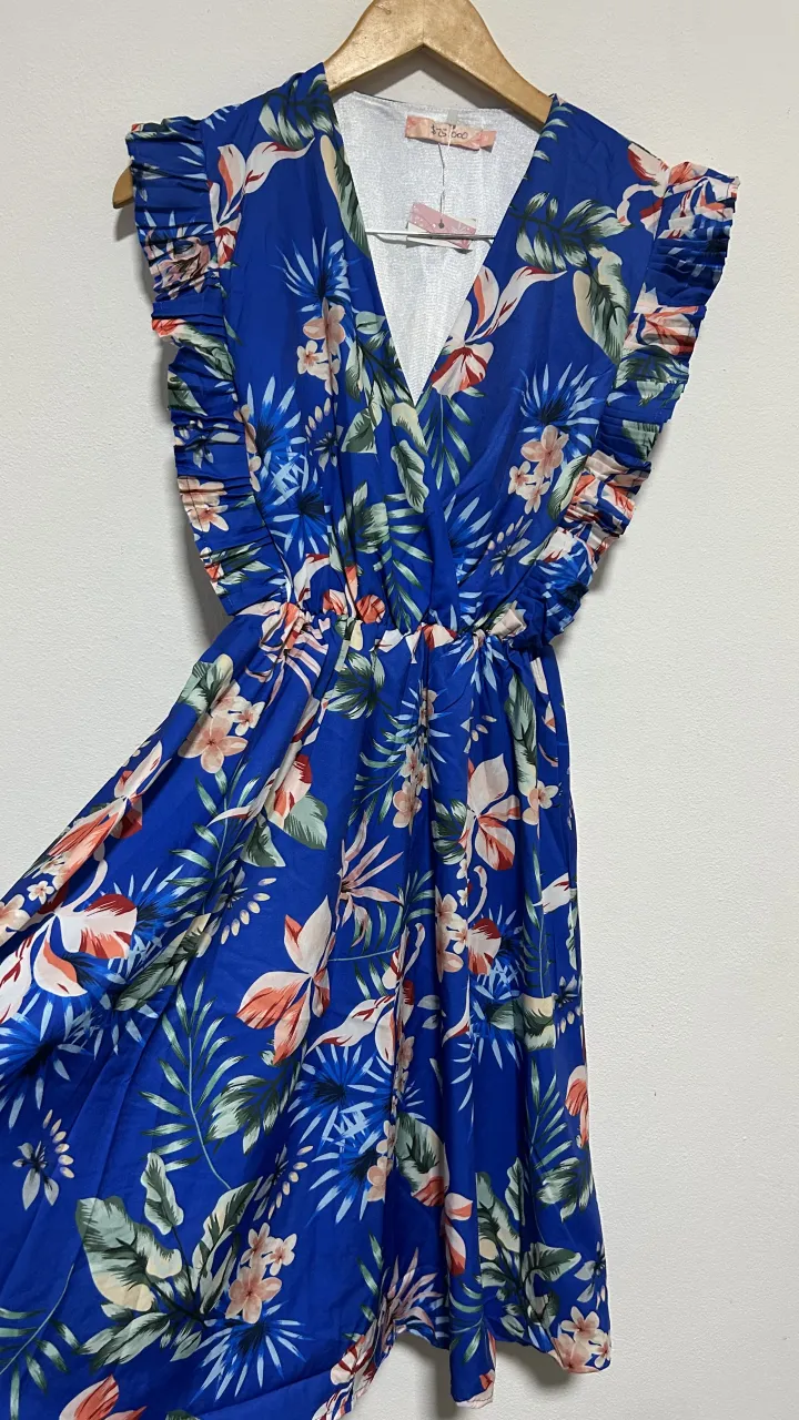 Vestido súper fresco y vibrante, ideal para el verano. Posee un estampado floral tropical en tonos azules, verdes, rosas y naranjas que le da un toque alegre y playero. Su diseño con volados en las mangas y escote en V lo hace súper femenino y canchero. Perfecto para lucir en días soleados, salidas casuales o vacaciones.