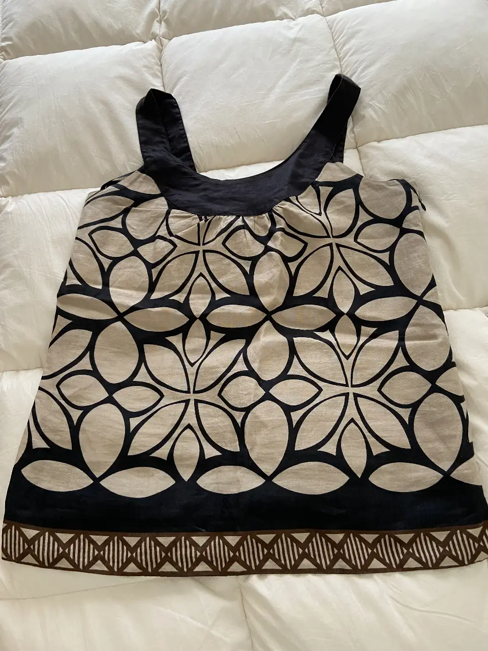 Top sin mangas con estampado floral en tonos neutros y detalles en negro. Ideal para un look fresco y moderno.