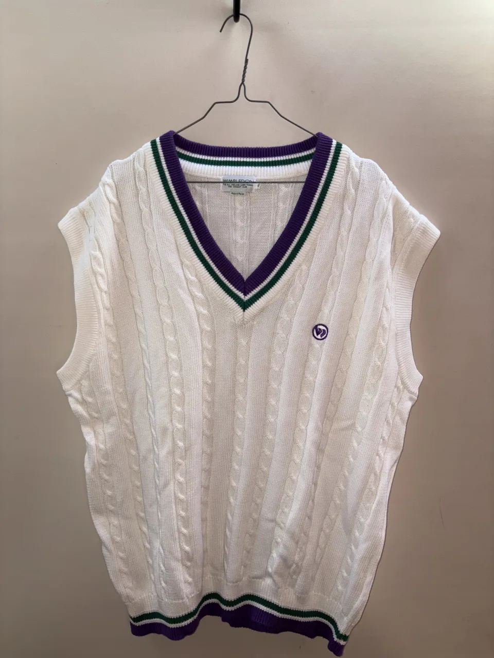 Chaleco de tejido blanco con cuello V y detalles de rayas en verde y violeta.