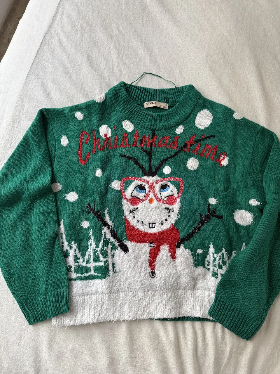 Sweater navideño verde con diseño de muñeco de nieve con anteojos rojos y la frase "Christmas time" en rojo. Ideal para celebrar las fiestas con estilo y diversión.