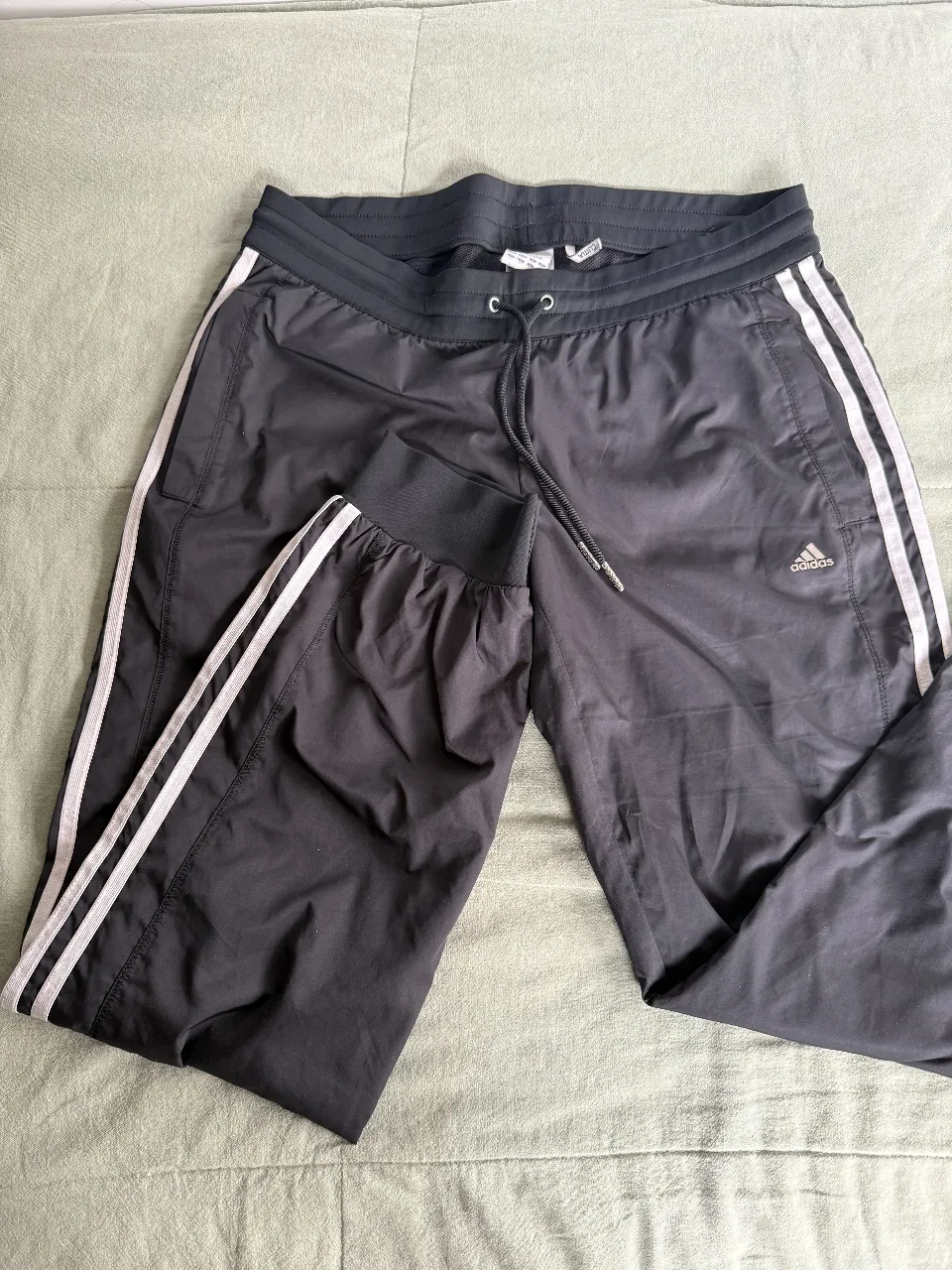 Pantalón deportivo Adidas negro con las tres tiras blancas a los costados. Talle M.