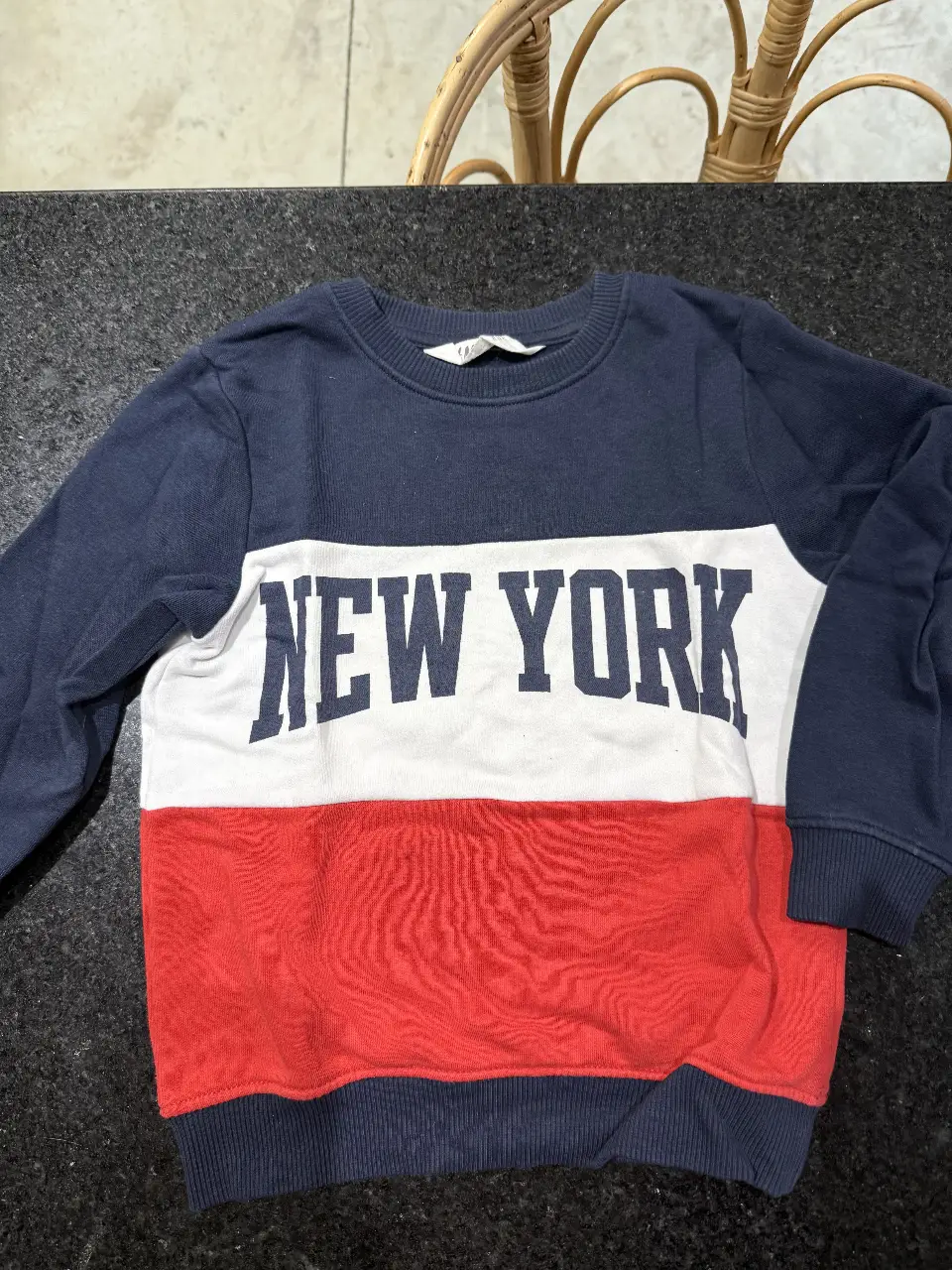 Buzo de cuello redondo para niño, con diseño "NEW YORK" en blanco sobre fondo azul marino, con una franja roja en la parte inferior. Ideal para un look casual y cómodo.