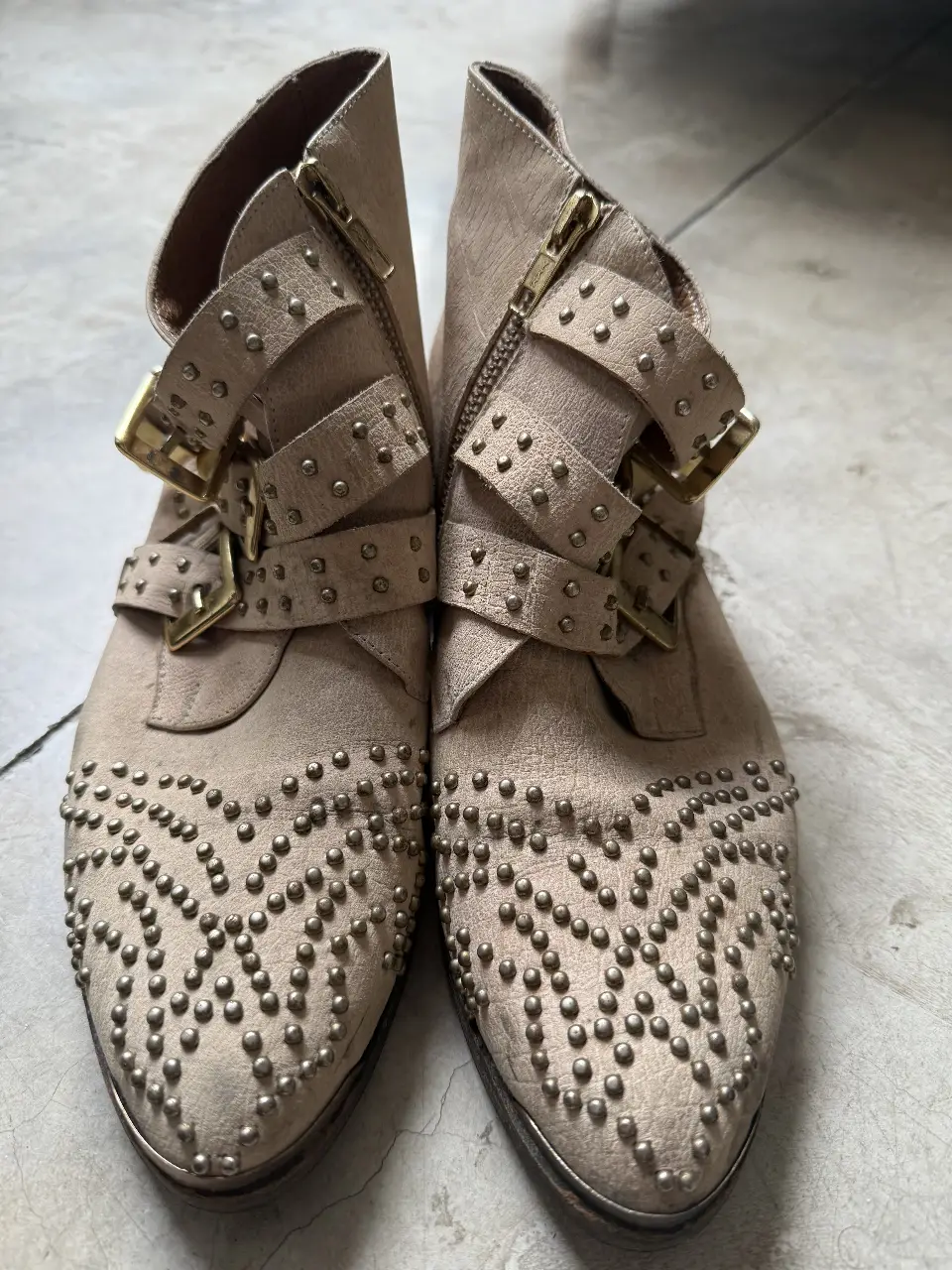 Botines de gamuza color crudo con tachas y hebillas doradas. talle 38 arg Tienen cierre lateral y detalles de diseño.