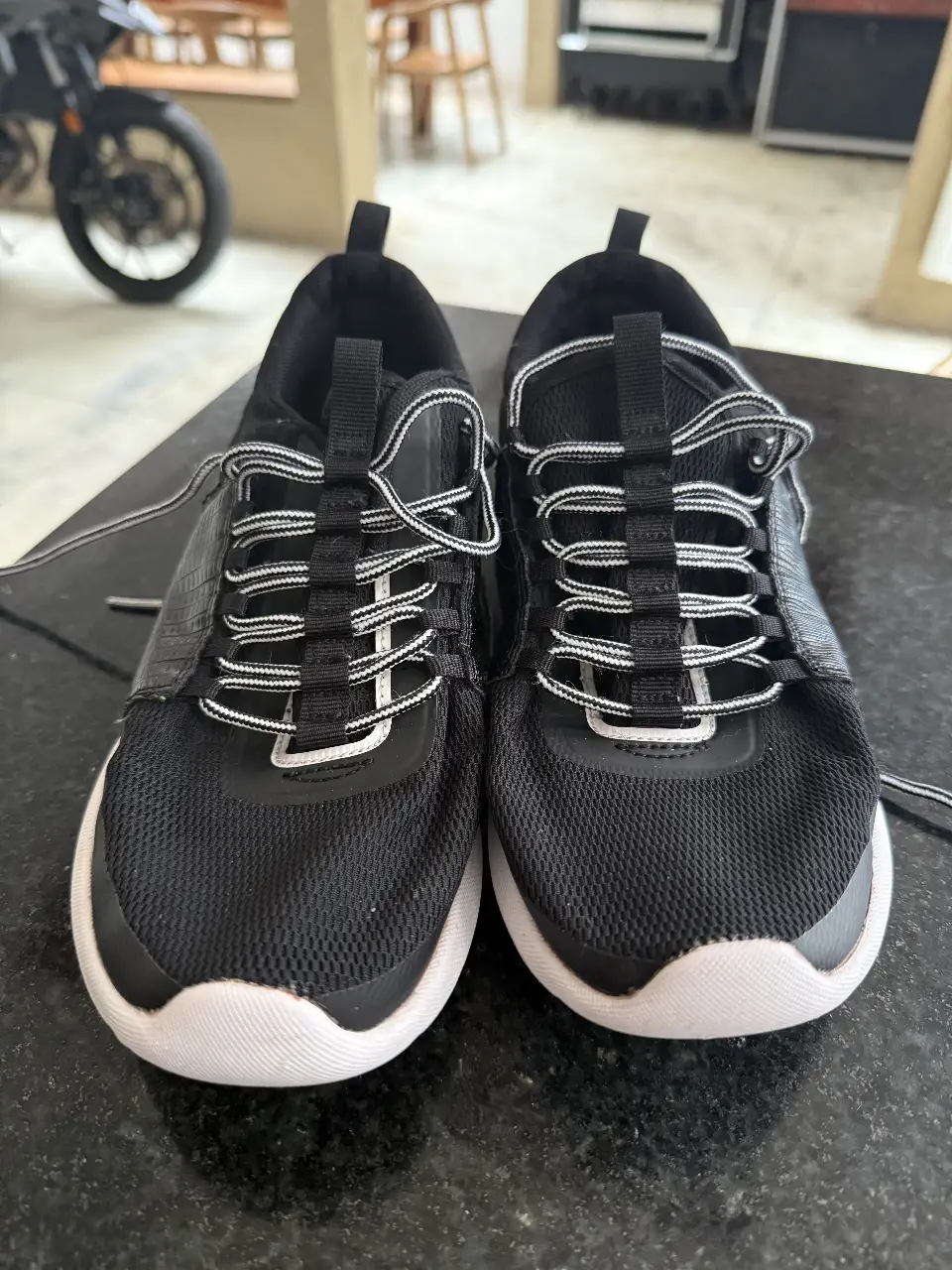 Zapatillas deportivas negras con detalles blancos. Ideales para running o uso diario. Tienen cordones blancos y suela blanca. talle 38 24,5 cm
