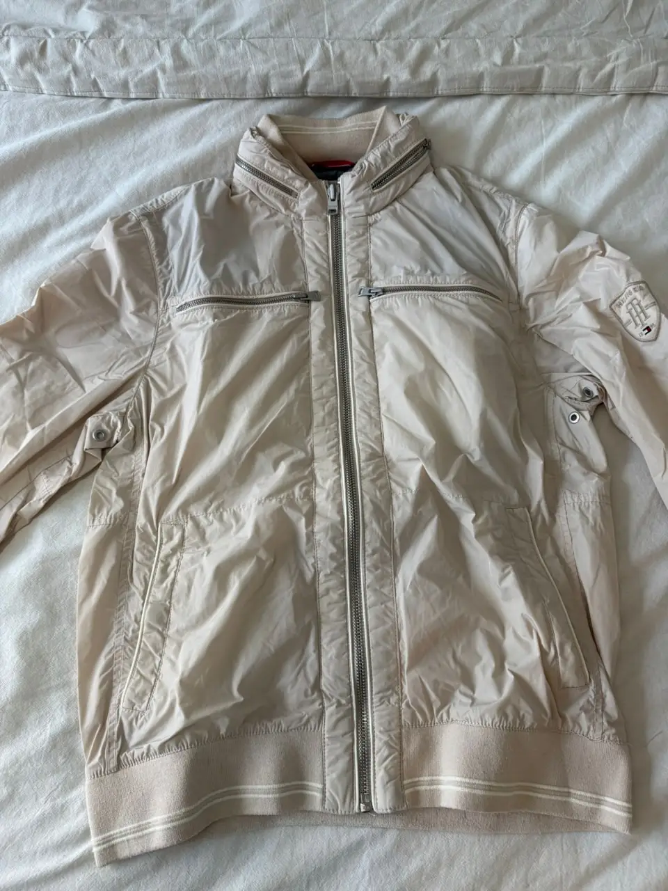 Campera Tommy Hilfiger color crudo para hombre, con cierre y bolsillos. Ideal para un look casual y moderno.